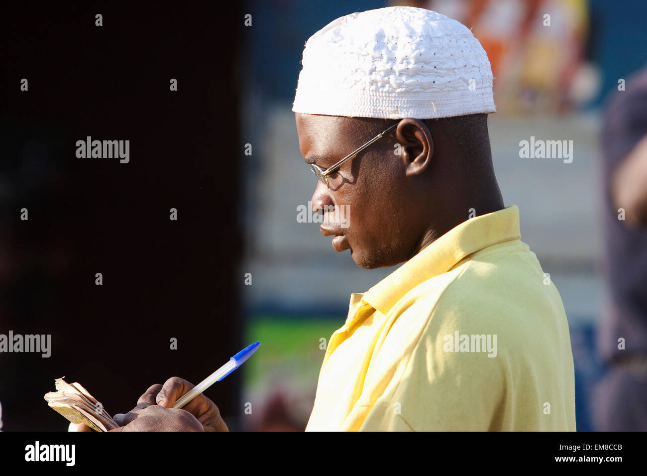 Vista laterale di un giovane uomo di scrittura in agenda a Bamako, in Mali Foto Stock