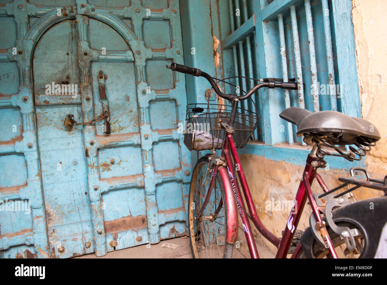 Una bicicletta accanto a un ornato porta blu su una strada posteriore in Fort Kochi, Kerala India Foto Stock