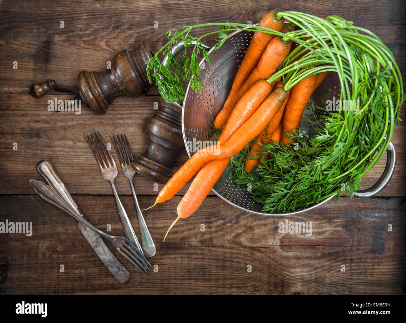 Carote radici con foglie verdi su legno rustico sfondo. Vegetali. In stile vintage food concept Foto Stock