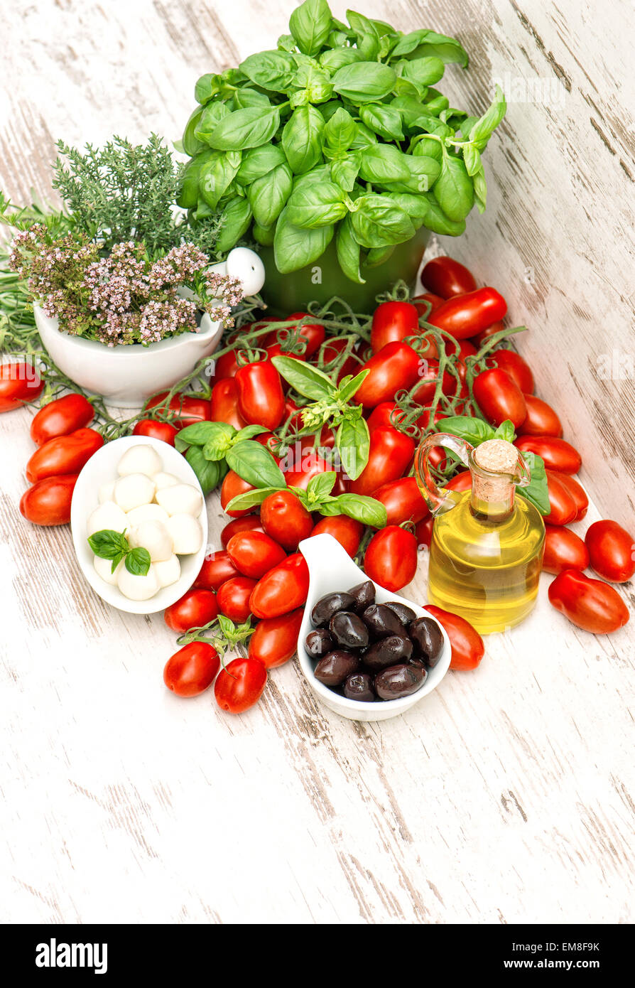 Le erbe fresche basilico, pomodori, mozzarella e olio di oliva. Cibo sano e background. Insalata Caprese ingredienti Foto Stock