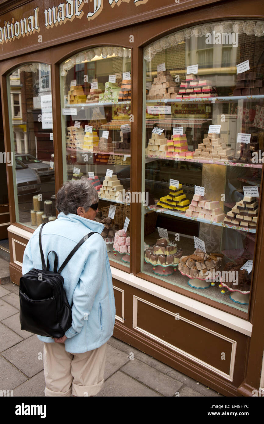 Regno Unito, Inghilterra, Yorkshire, Scarborough, Eastborough, senior donna cercando in vecchio stile Fudge vetrina Foto Stock