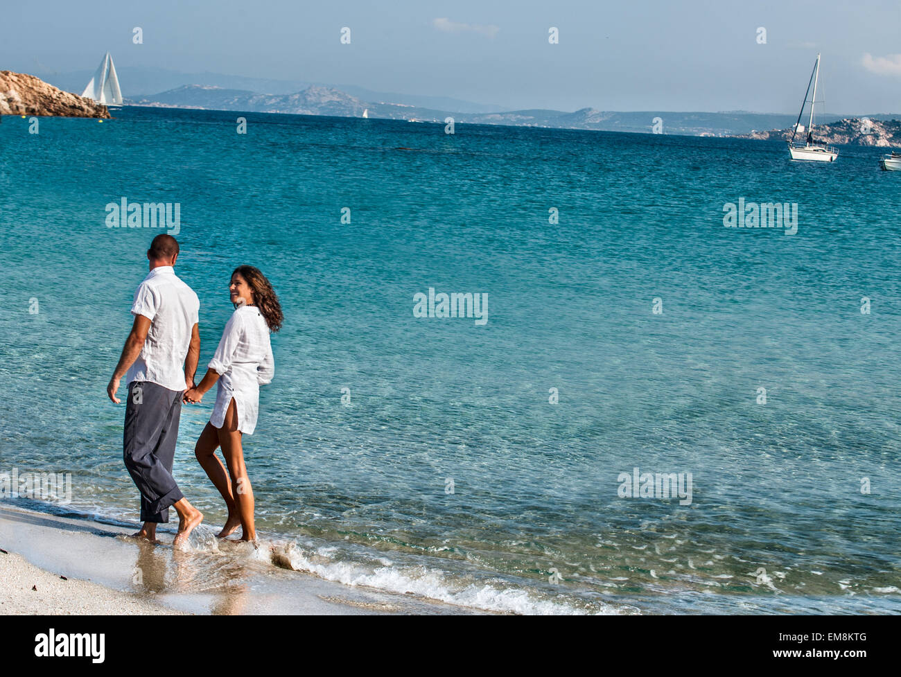 Giovane camminando mano nella mano lungo la spiaggia Foto Stock