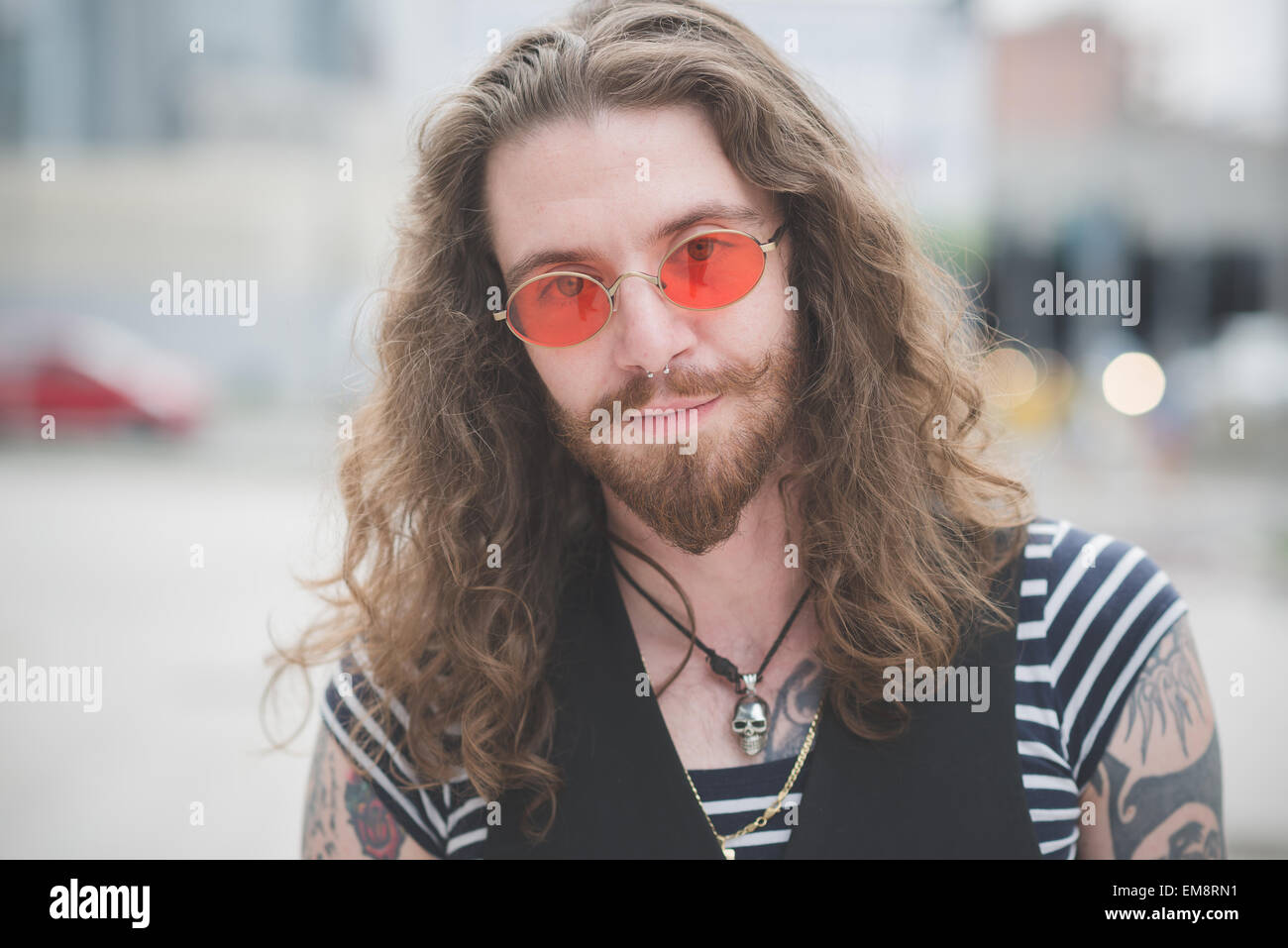 Ritratto di giovane maschio hippy con orange occhiali da sole e capelli lunghi Foto stock Alamy