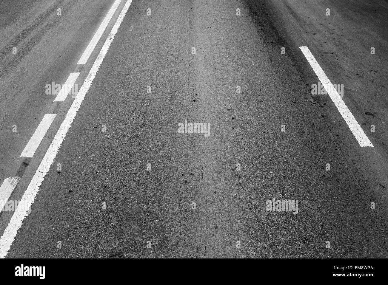 Strada asfaltata con linee divisorie e tracce di pneumatici. Foto di sfondo con effetto prospettico Foto Stock