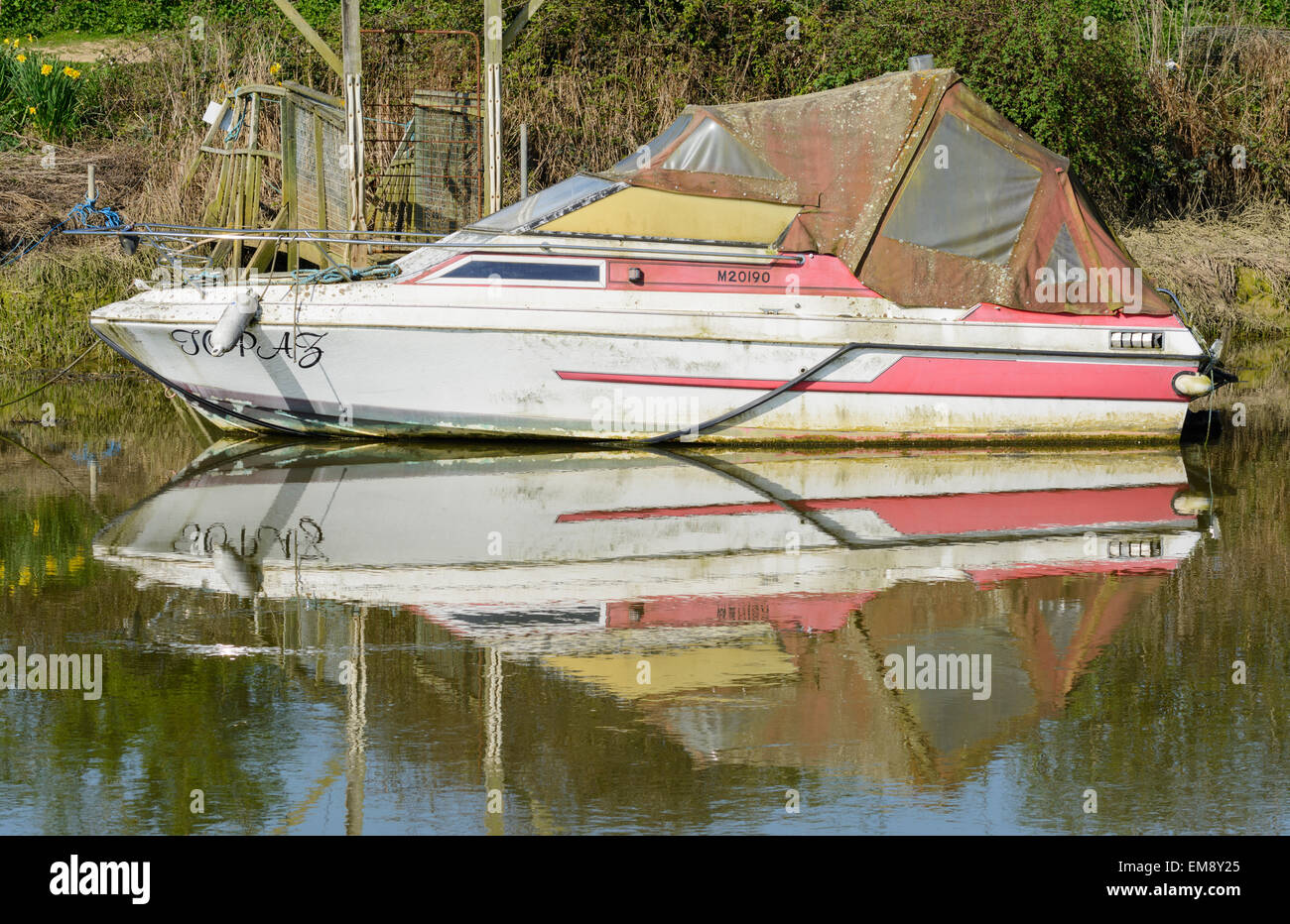 Piccola barca ormeggiata su un fiume con il suo riflesso nell'acqua. Foto Stock