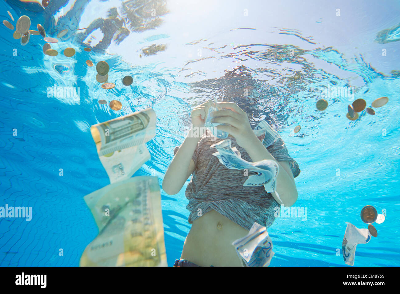 Vista subacquea del ragazzo in piscina grabbing valuta euro Foto Stock