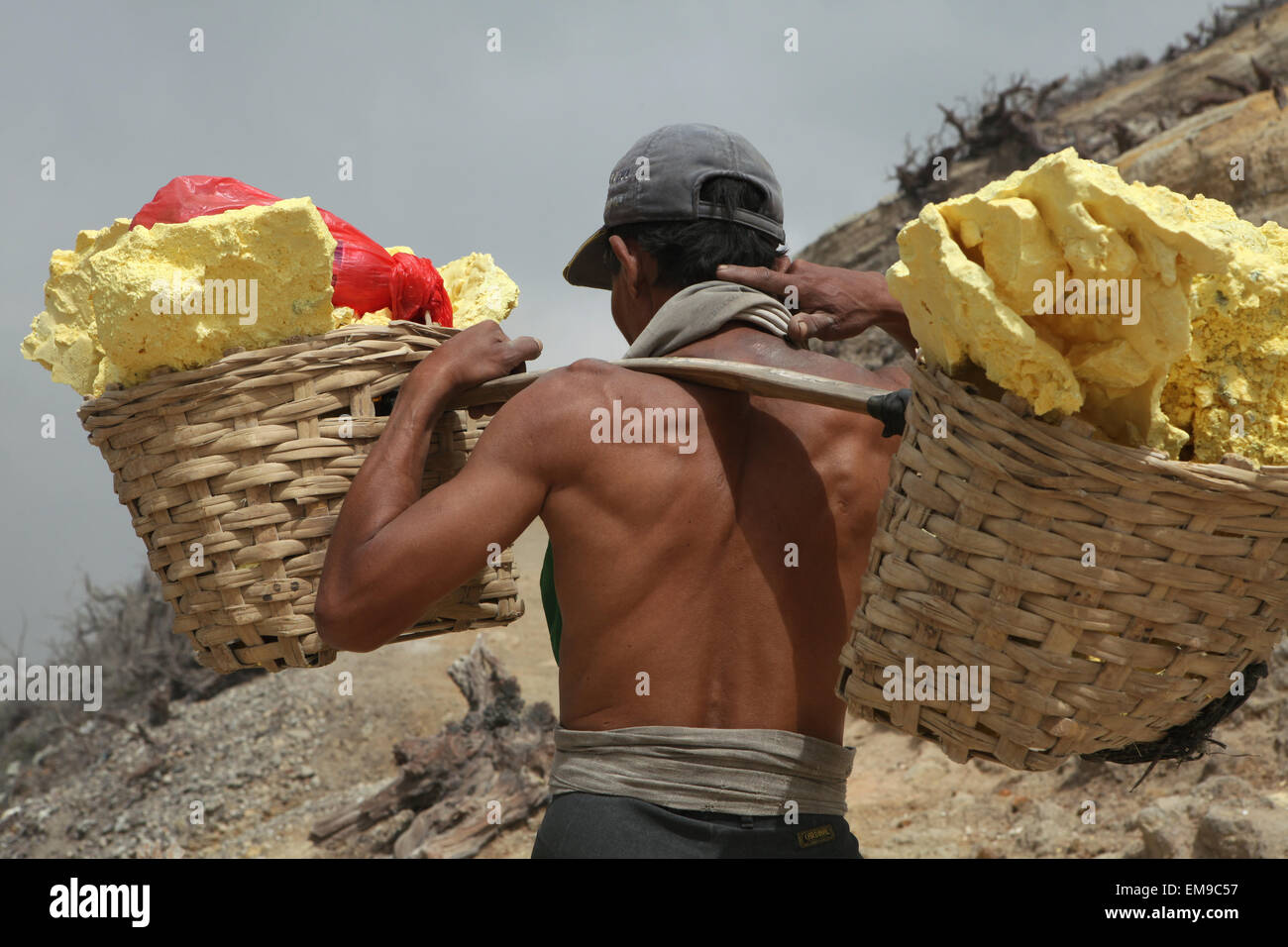 Miniere di zolfo Kawah Ijen, Java Orientale, Indonesia. Il minatore porta cesti con zolfo nei fumi tossici i gas vulcanici. Foto Stock