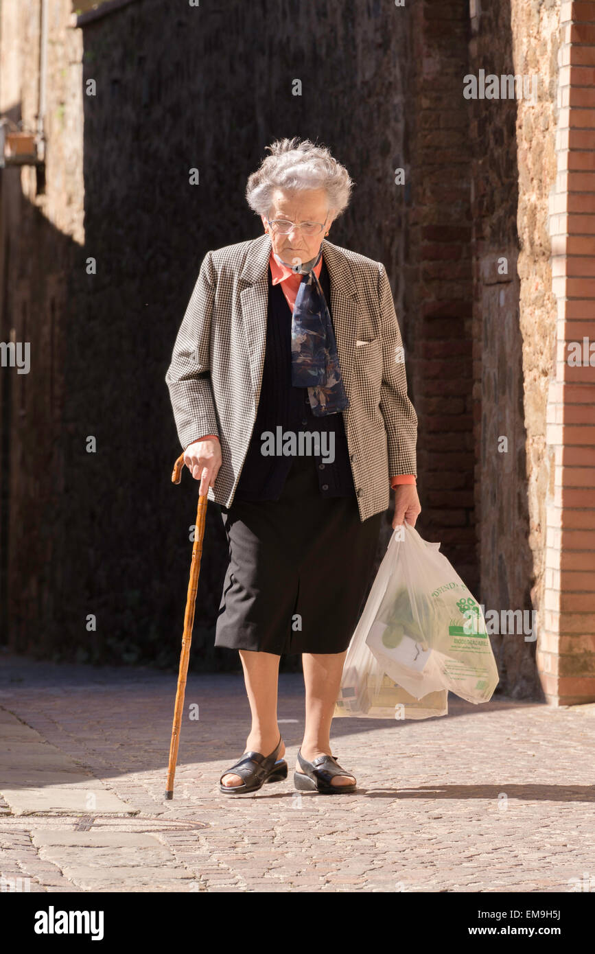 Old Lady andando a casa da shopping a Montalcino, Toscana, Italia Foto Stock