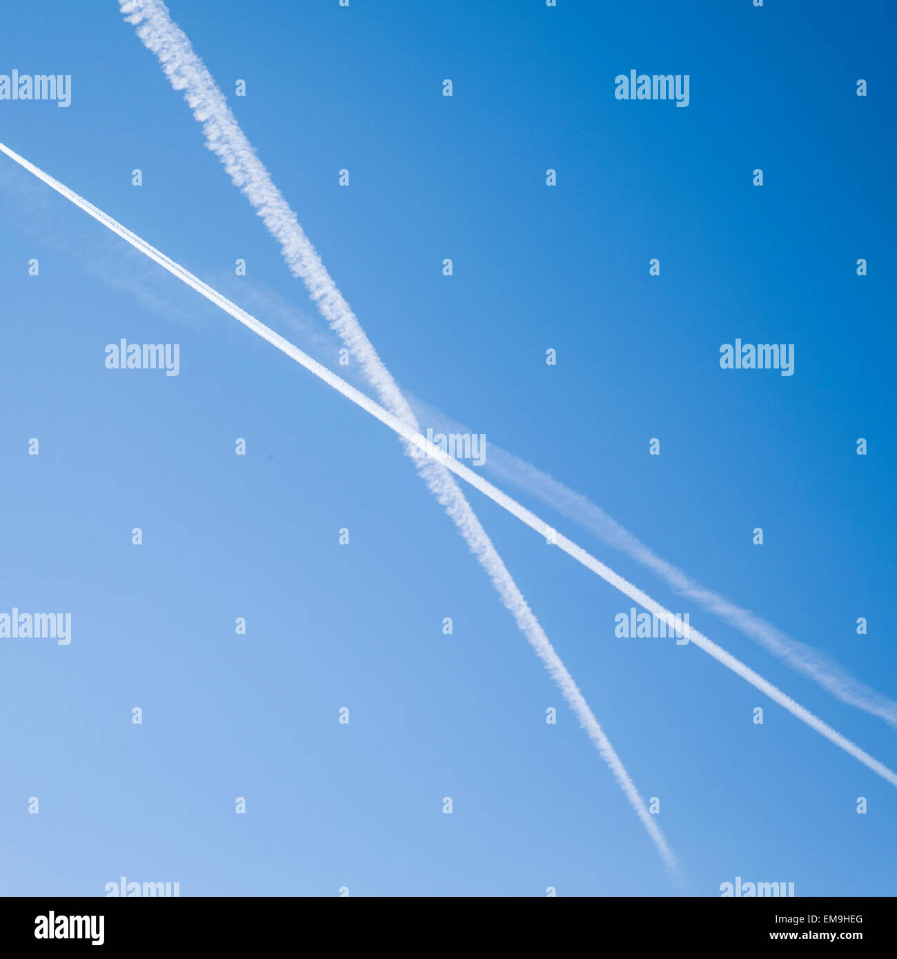 Piano di Jet contrails striature in un X configurazione attraverso un luminoso cielo blu. Foto Stock