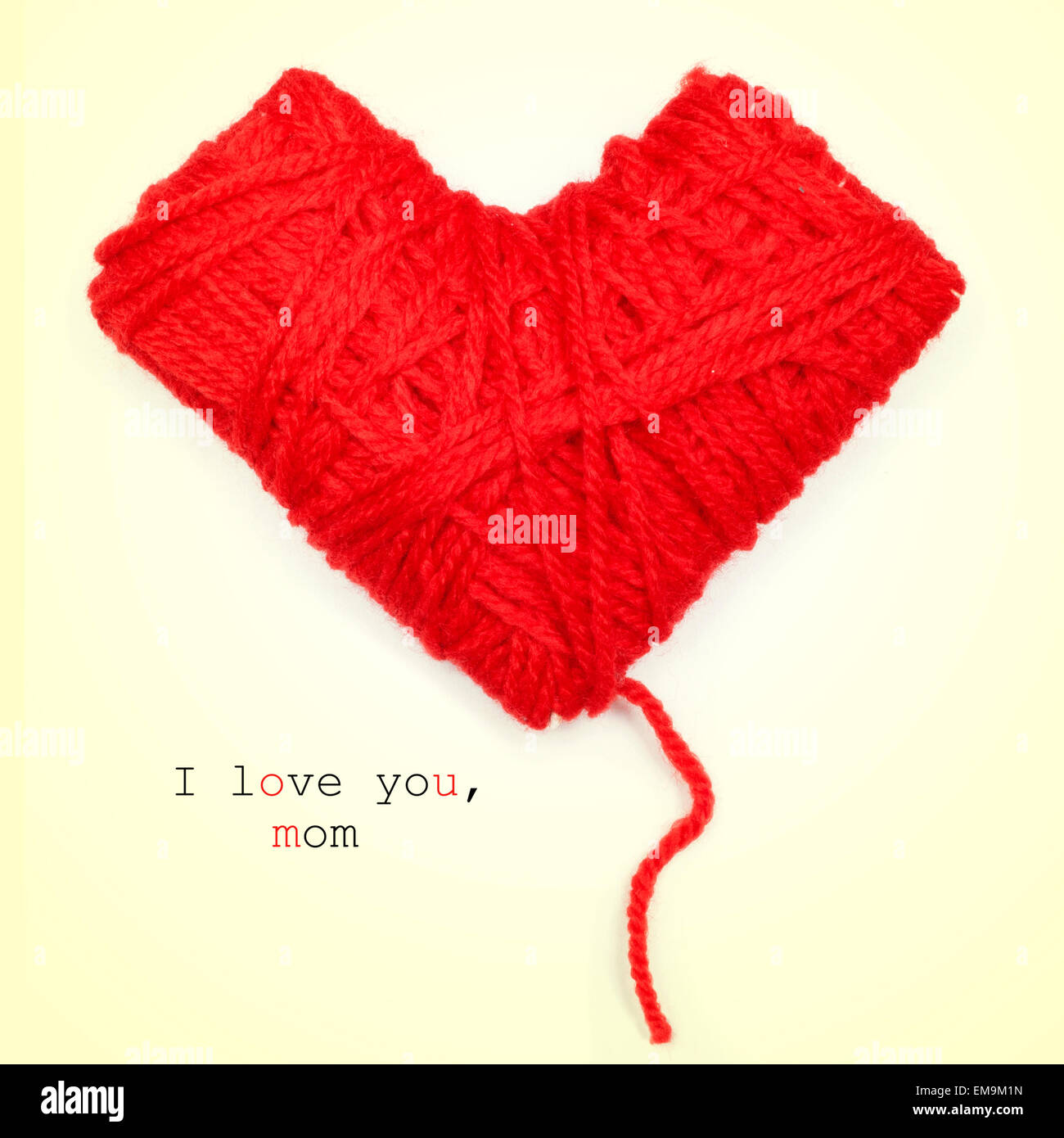 Primo piano di un cuore a forma di bobina di filo rosso e il testo ti amo, MOM, su uno sfondo beige Foto Stock