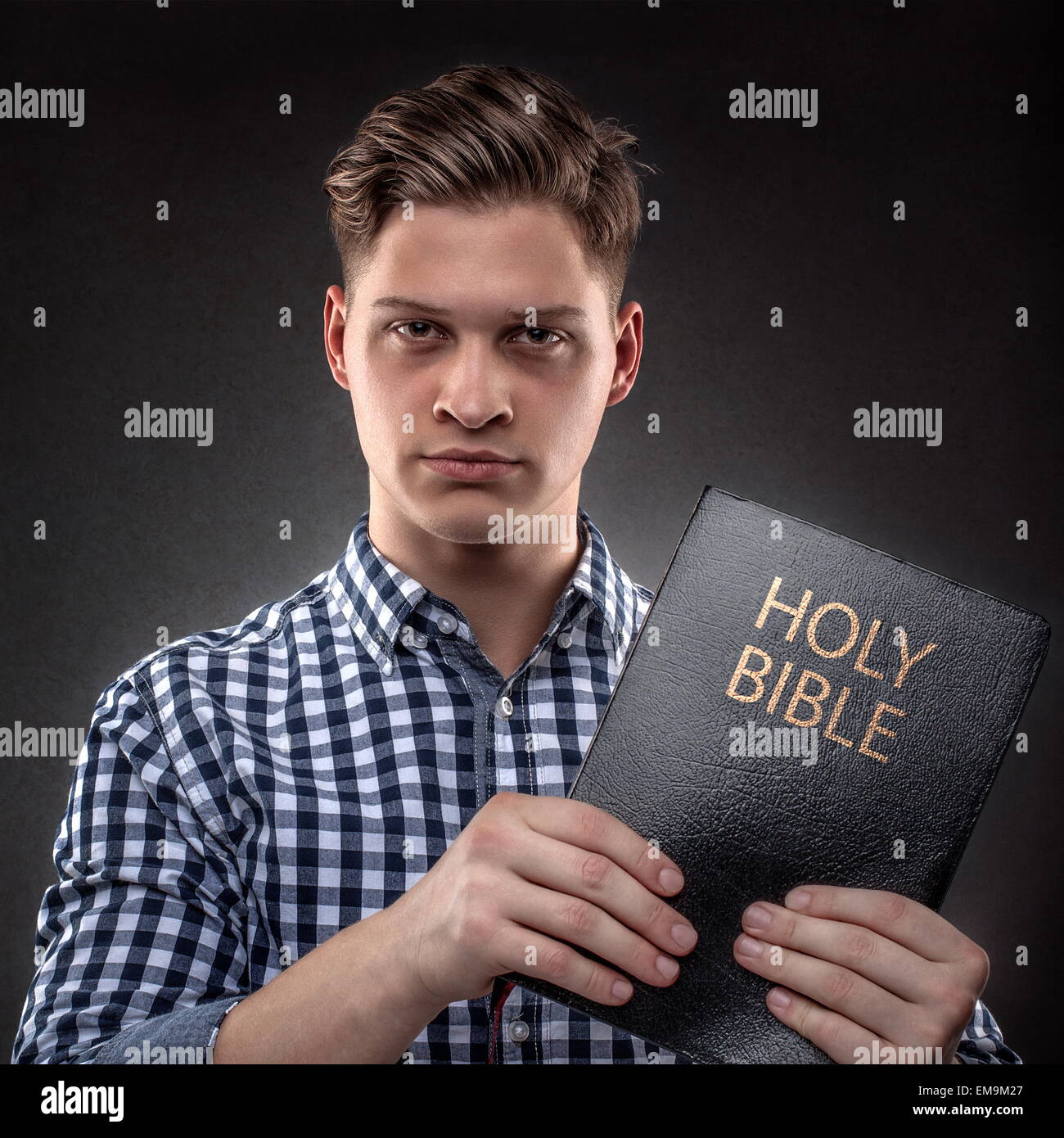 Giovane cristiano che mostra che mostra con determinazione una Sacra Bibbia (concetto contro la tentazione dalla Parola di Dio) Foto Stock