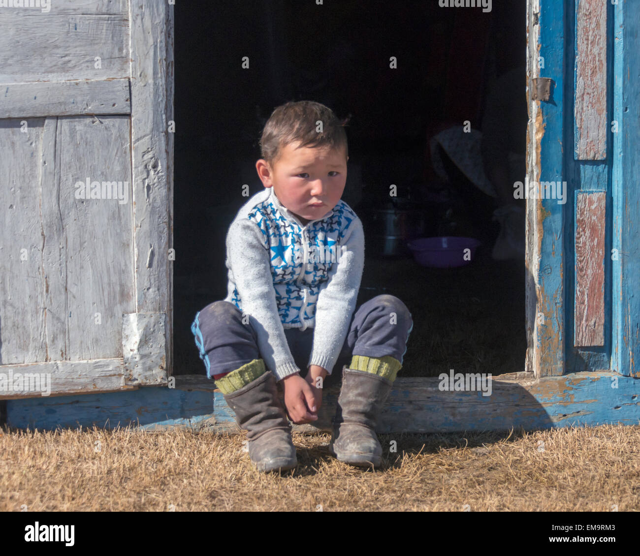 Giovane ragazzo kazako seduto fuori un ger, Mongolia occidentale Foto Stock