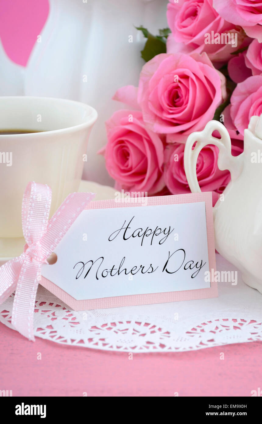 Felice Festa della Mamma Rosa Rose e bollitore tè e impostazione su shabby chic stile vintage invecchiato in legno rosa tabella. . Foto Stock