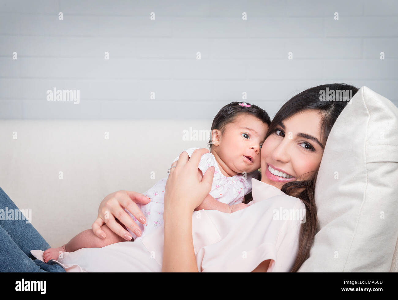 Felice madre con bambino sdraiato sul lettino a casa allegra donna che gioca con la sua adorabile figlia, di amore e di felicità Foto Stock