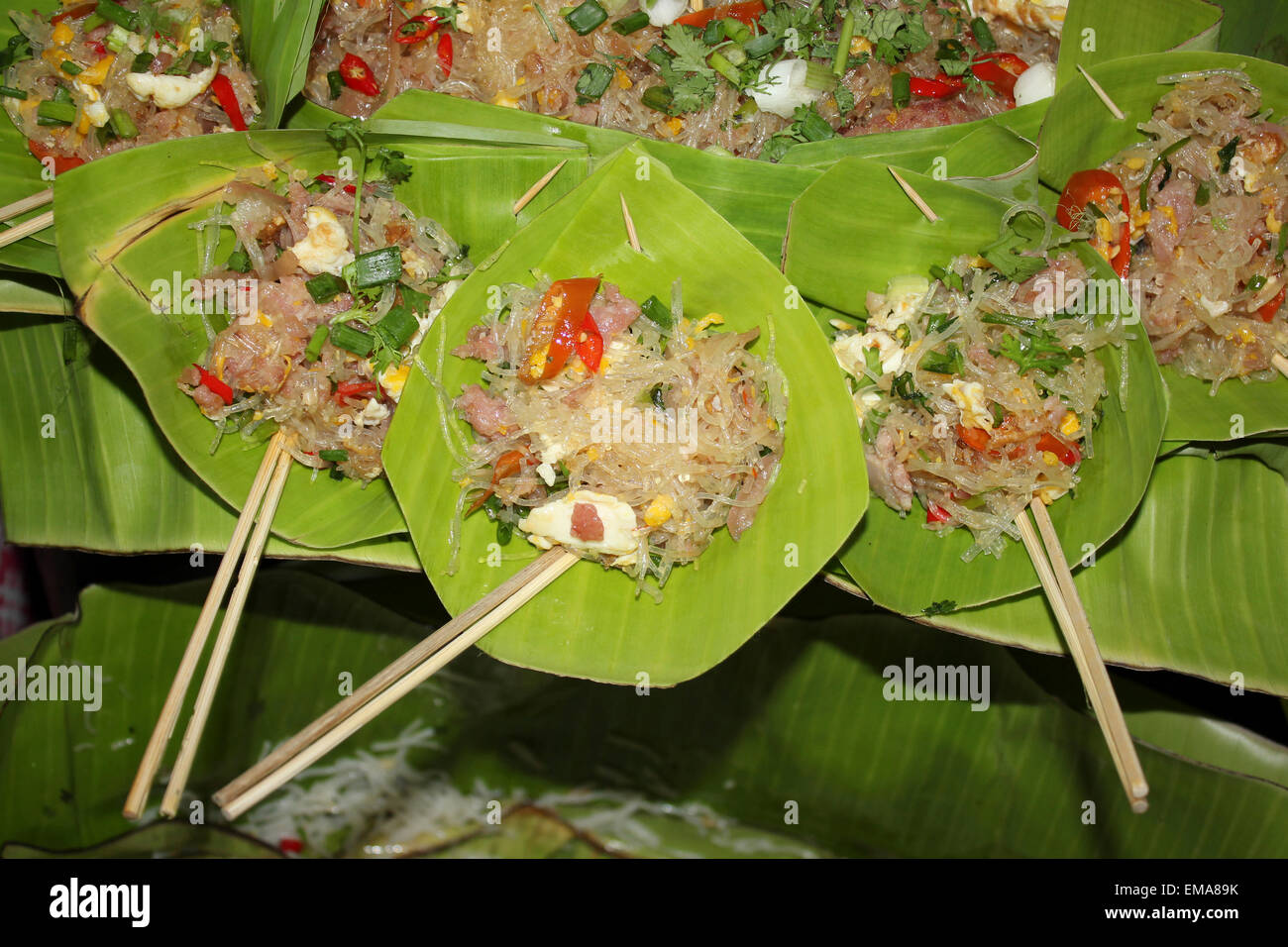 Local Thai Street Food di noodles fritti, Chilis e di carne macinata di maiale su di una piastra in foglia Foto Stock