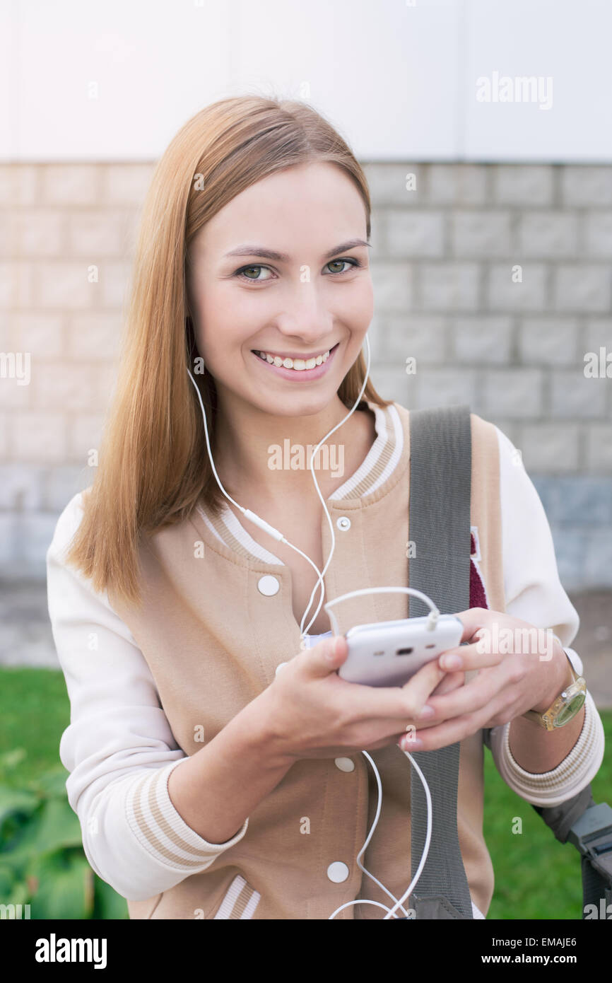 Studente ascoltando le cuffie e azienda mobile con due mani Foto Stock