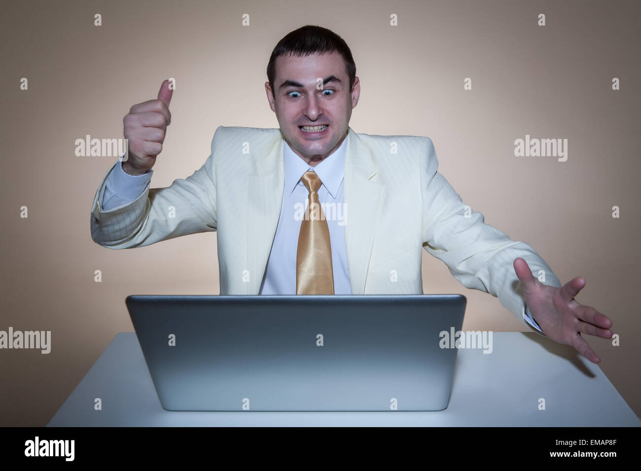 Un uomo in abito bianco seduto con un notebook. Rende i gesti delle mani. Vivide emozioni. Foto Stock