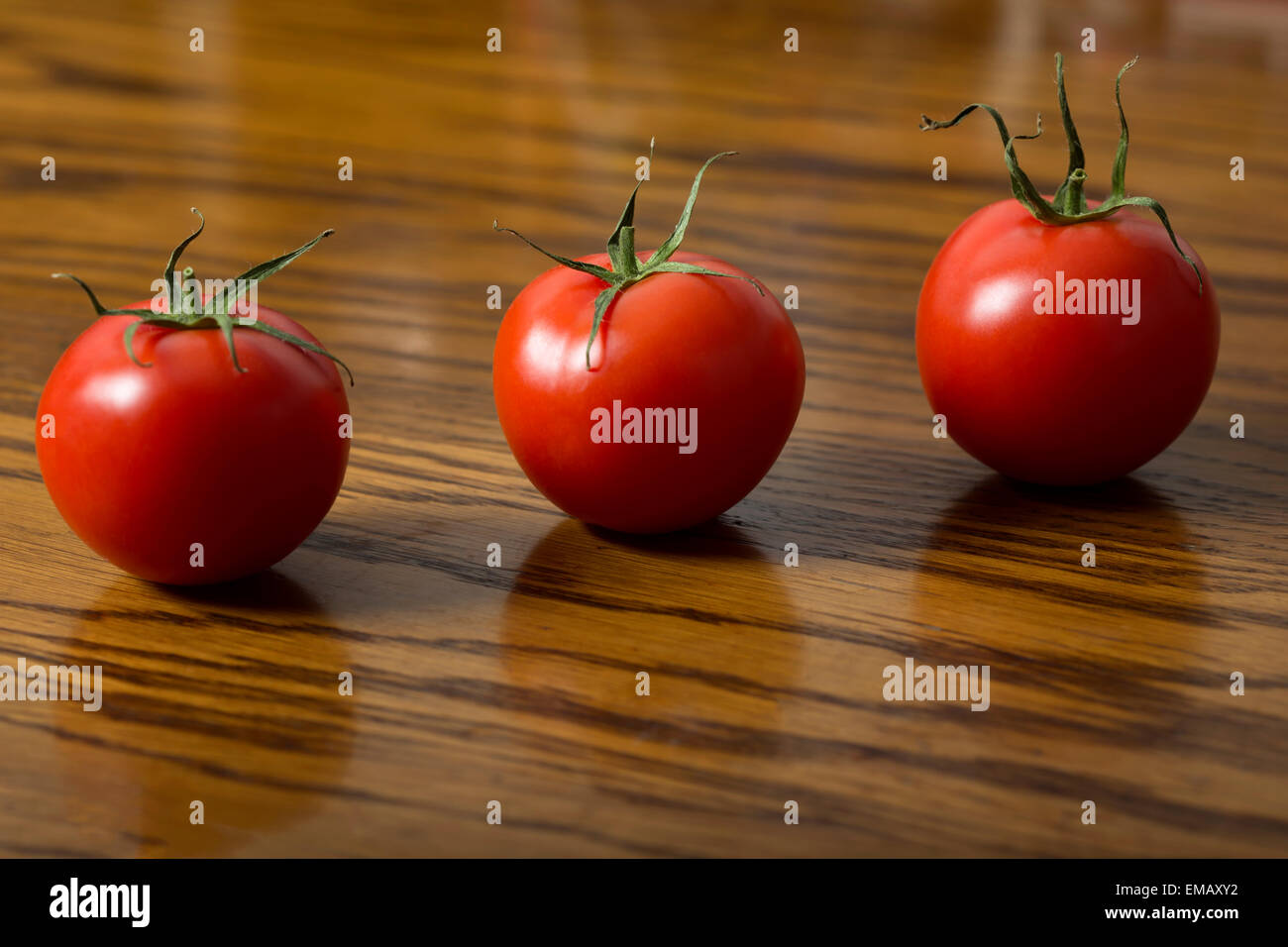 Tre pomodori in legno scuro, tabella Foto Stock