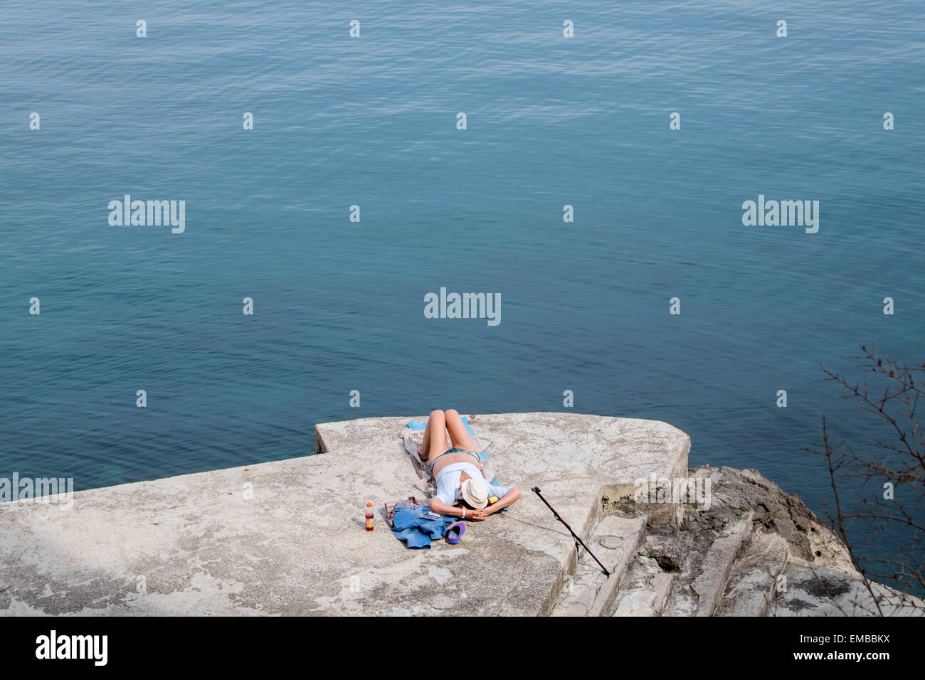 Una donna a prendere il sole su una spiaggia rocciosa di Opatija, Croazia Foto Stock