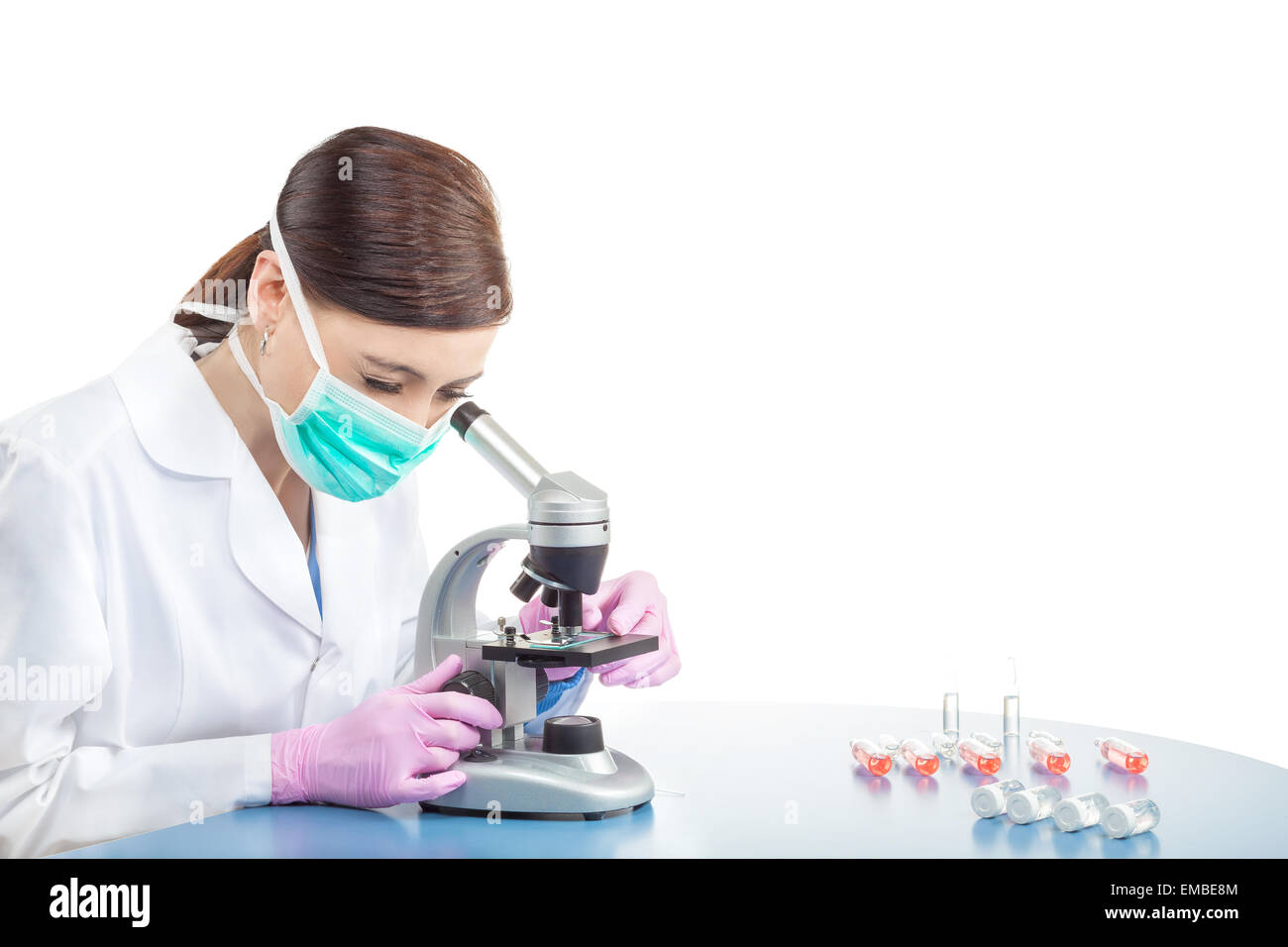 Medico donna o ricercatore scientifico in maschera mediante microscopio in un laboratorio, spazio per il testo. Foto Stock