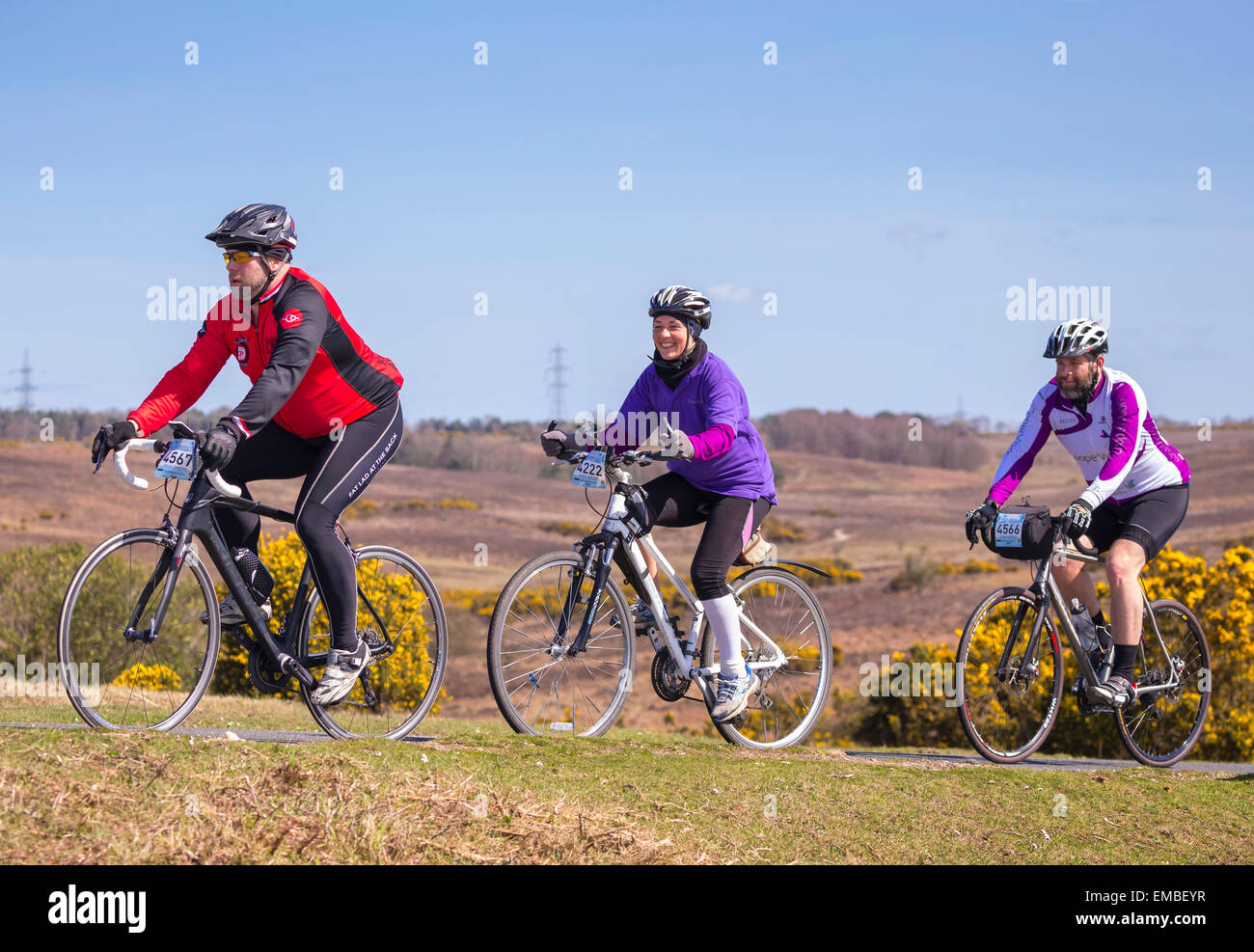 Due maschi e una femmina ciclisti competere nella nuova foresta dimenare evento sportivo su una soleggiata domenica di primavera Foto Stock