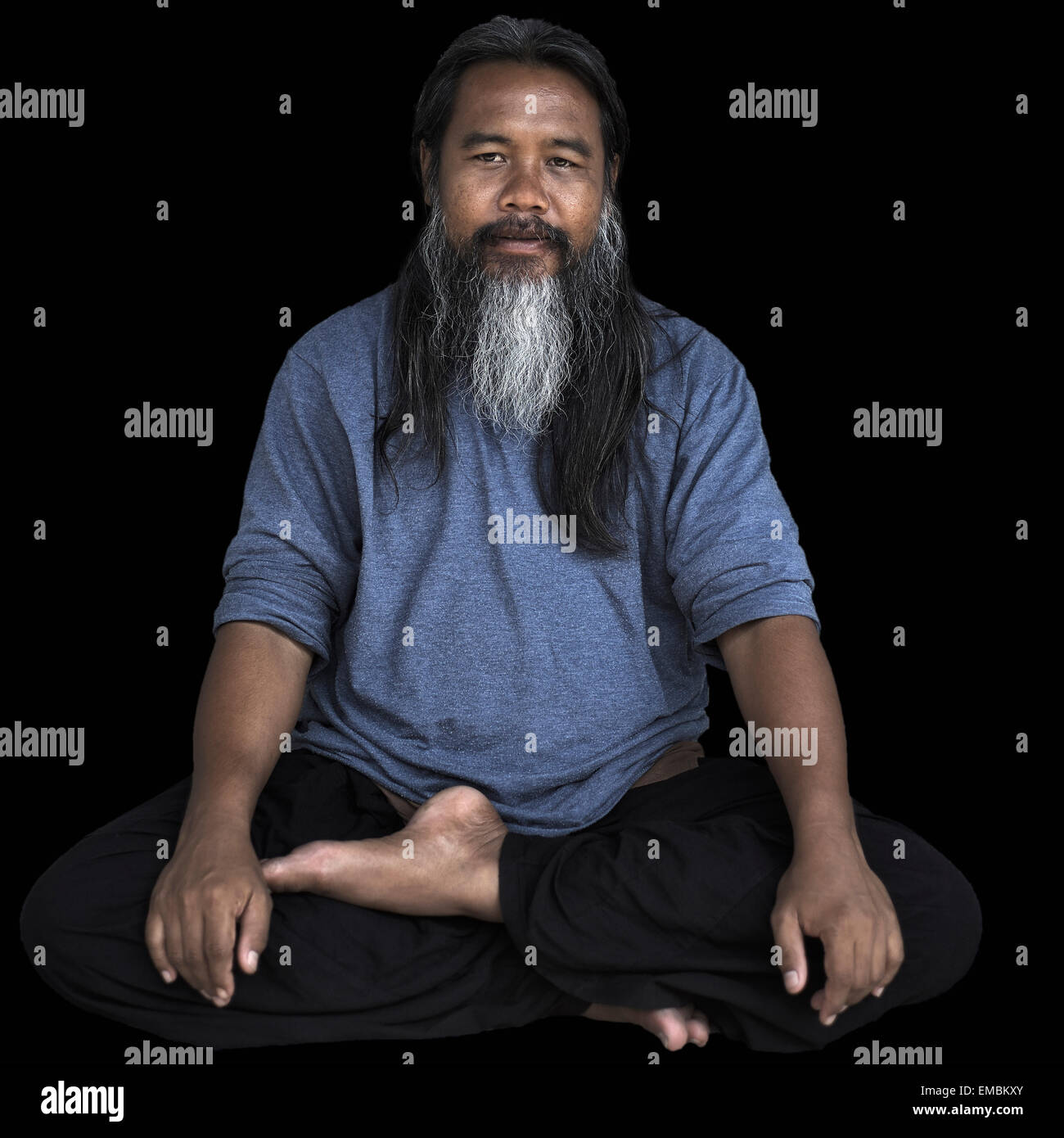 Uomo asiatico. Ritratto di un uomo barbuto thailandese seduto a gambe incrociate in stile yoga posizione. Foto Stock