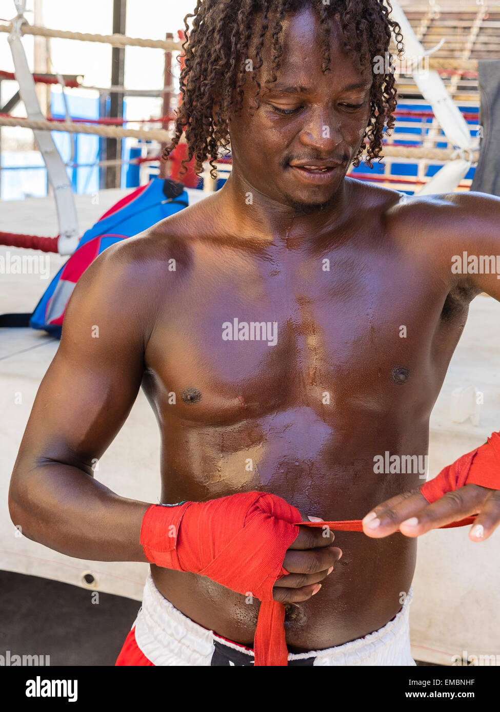 Close-up verticale di un pugile afro-cubane a mettere su una sua mano rossa avvolge durante una sessione presso il Rafael Trejo Boxing palestra. Foto Stock
