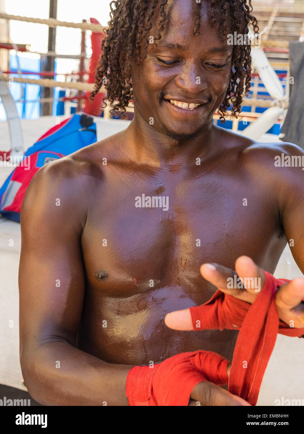 Close-up verticale di un pugile afro-cubane a mettere su una sua mano rossa avvolge durante una sessione presso il Rafael Trejo Boxing palestra. Foto Stock