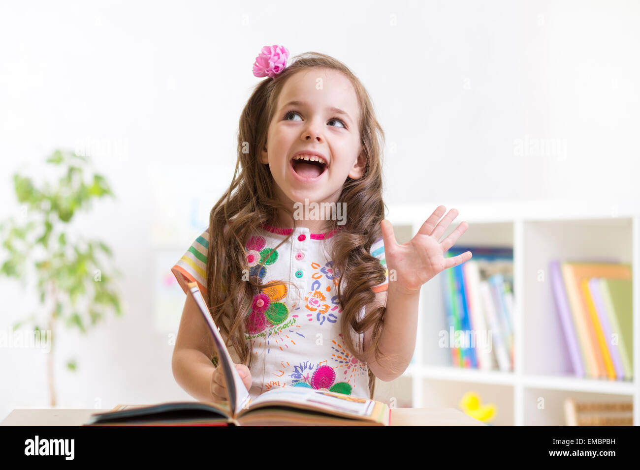 Bambino sorridente ragazza libro di lettura a casa Foto Stock