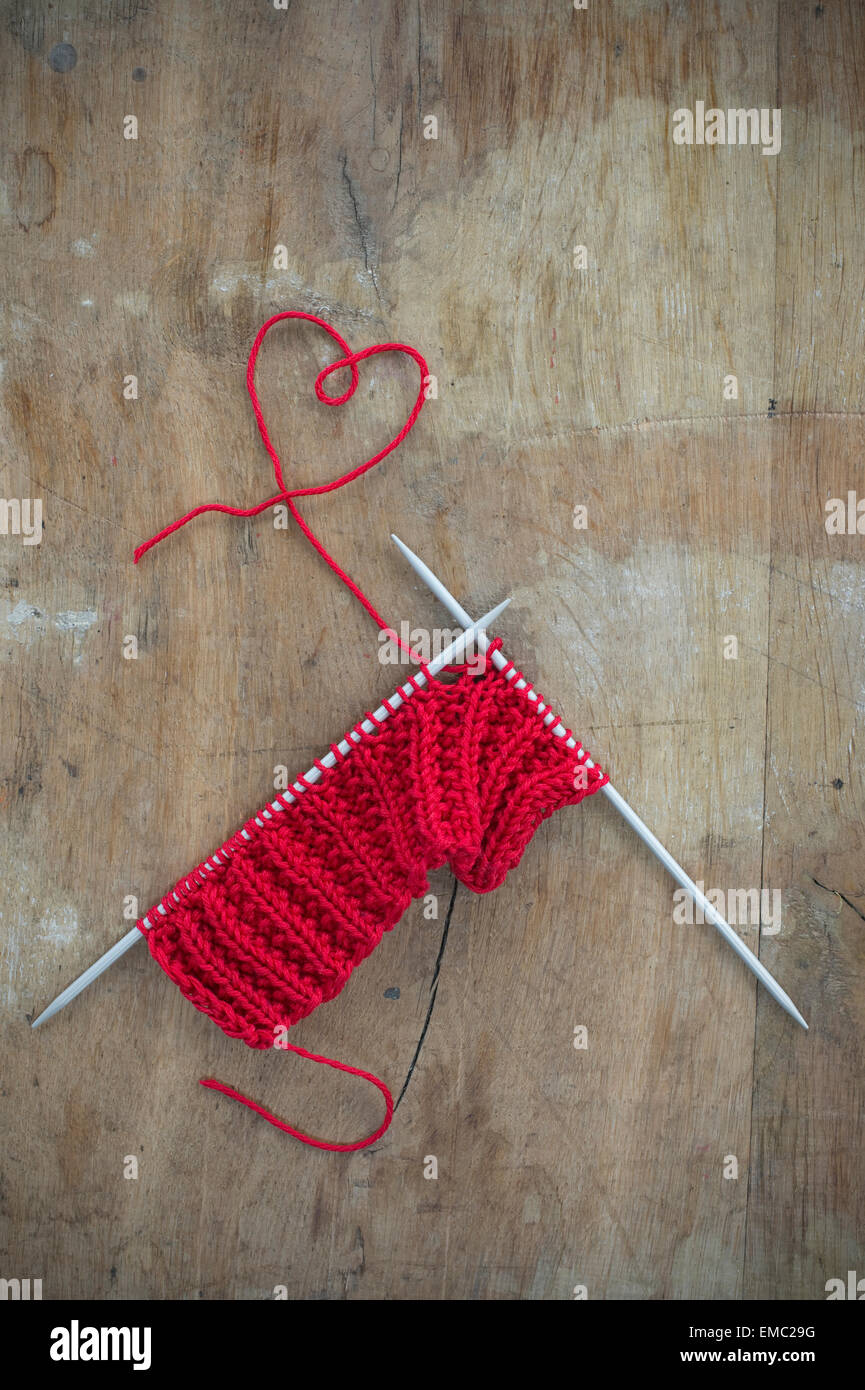 Maglia e filo sagomato come un cuore su legno Foto Stock