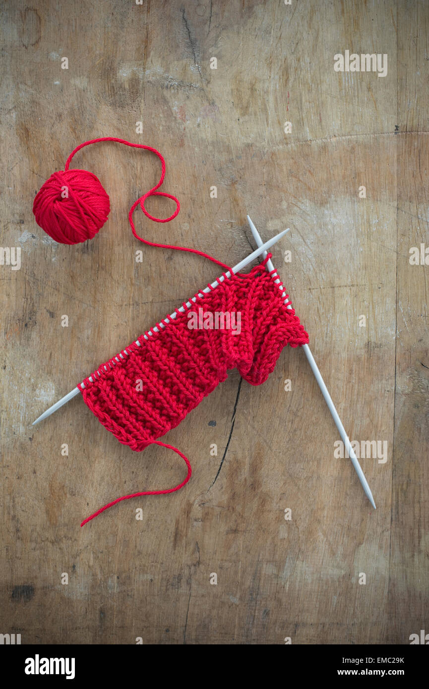 Sfera rossa di lana e maglia su legno Foto Stock