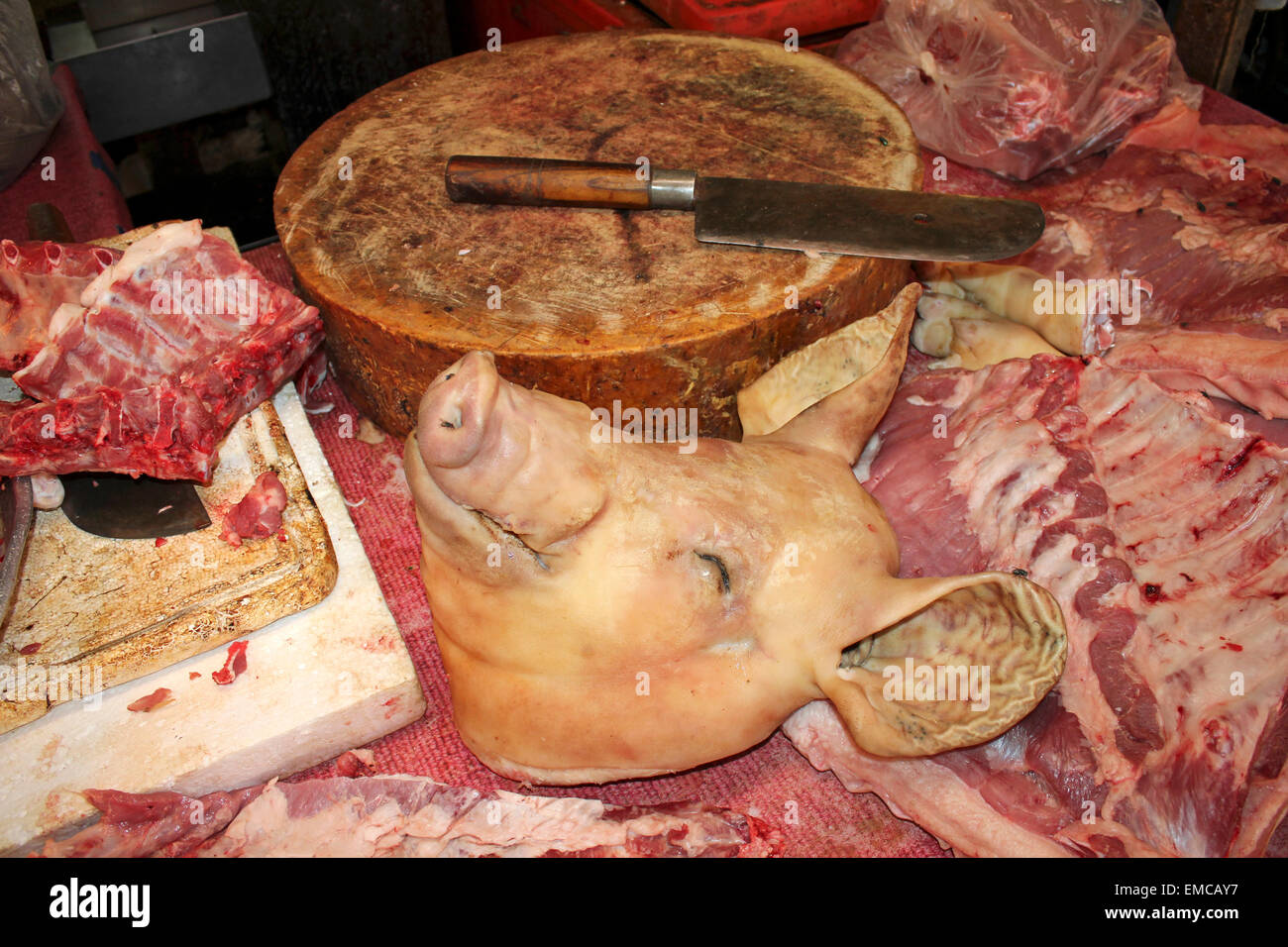 Del maiale accanto a testa di legno Blocco di trinciatura in un mercato macellai in Thailandia Foto Stock