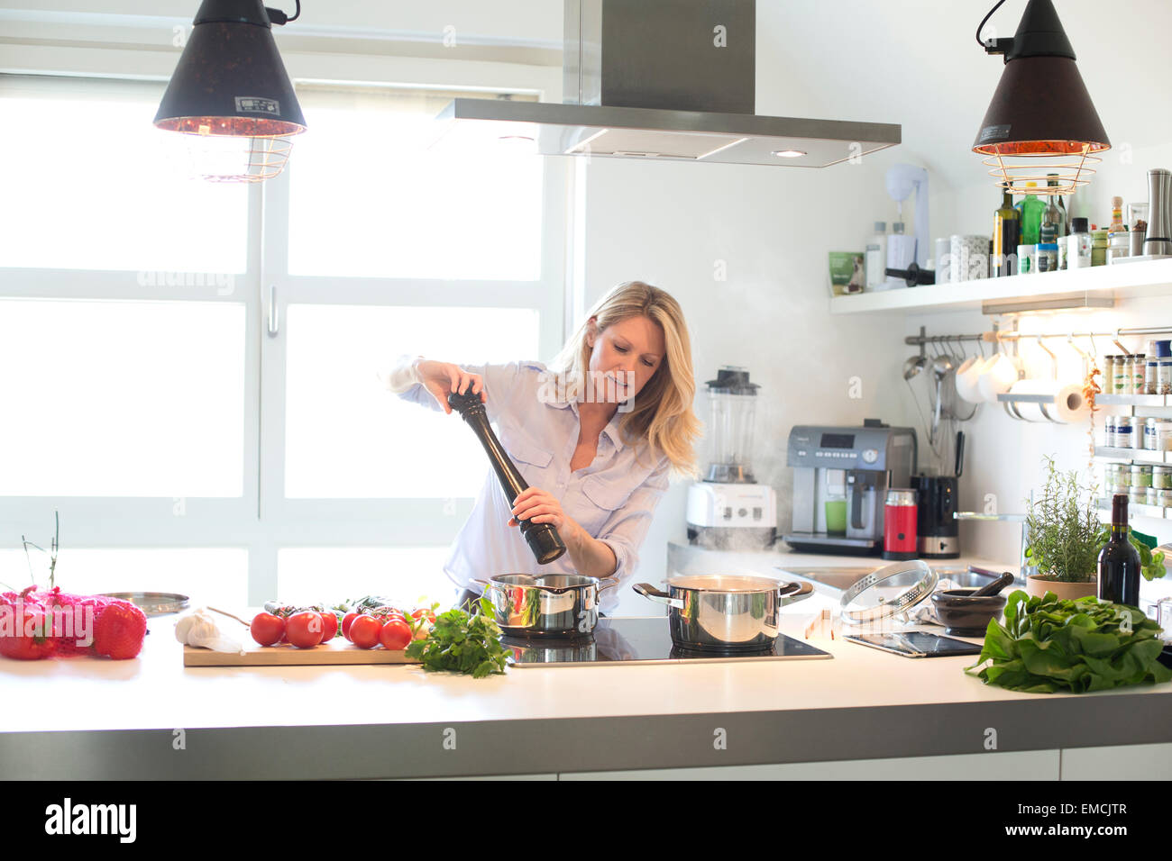 La donna la cottura in cucina utilizzando macinino pepe Foto Stock