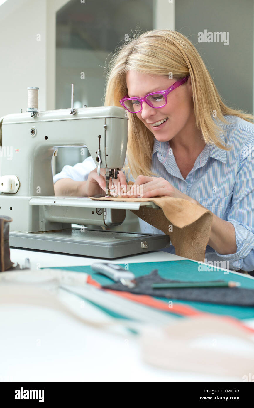 Donna sorridente lavorando sulla macchina da cucire Foto Stock