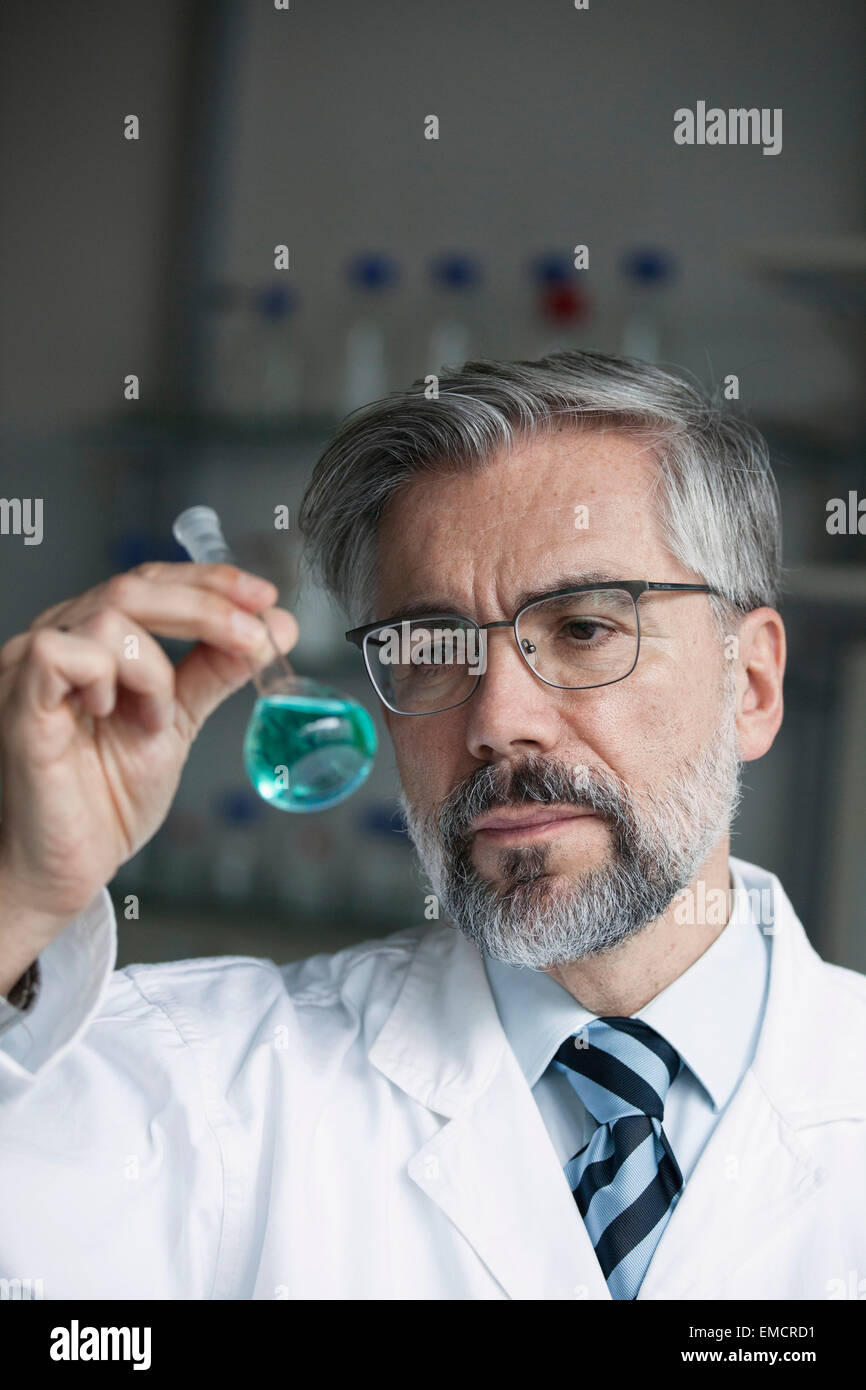 Scienziato in laboratorio esaminando il liquido nel pallone a fondo tondo Foto Stock
