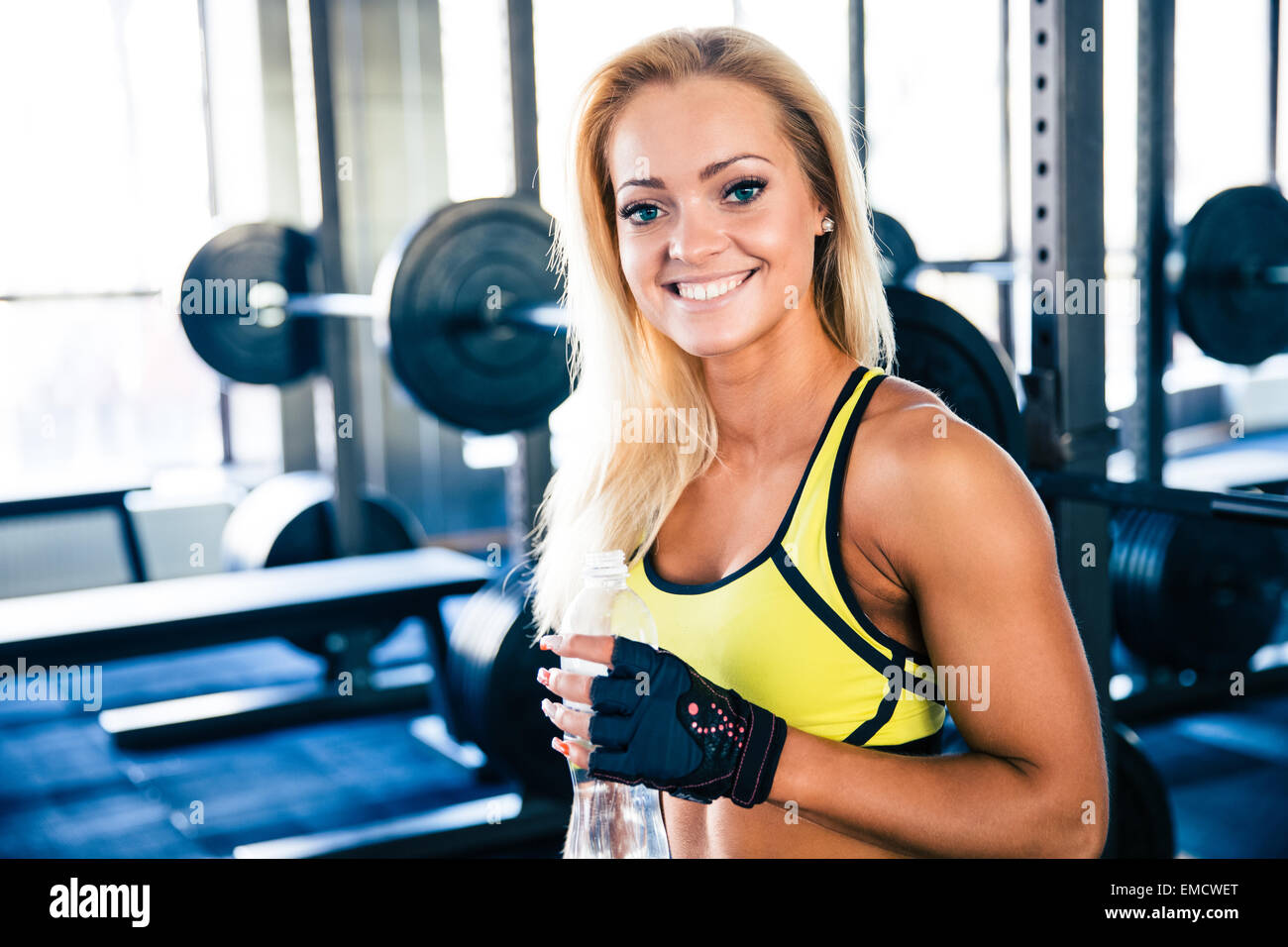 Ritratto ofa felice fit donna tenendo una bottiglia di acqua in palestra Foto Stock