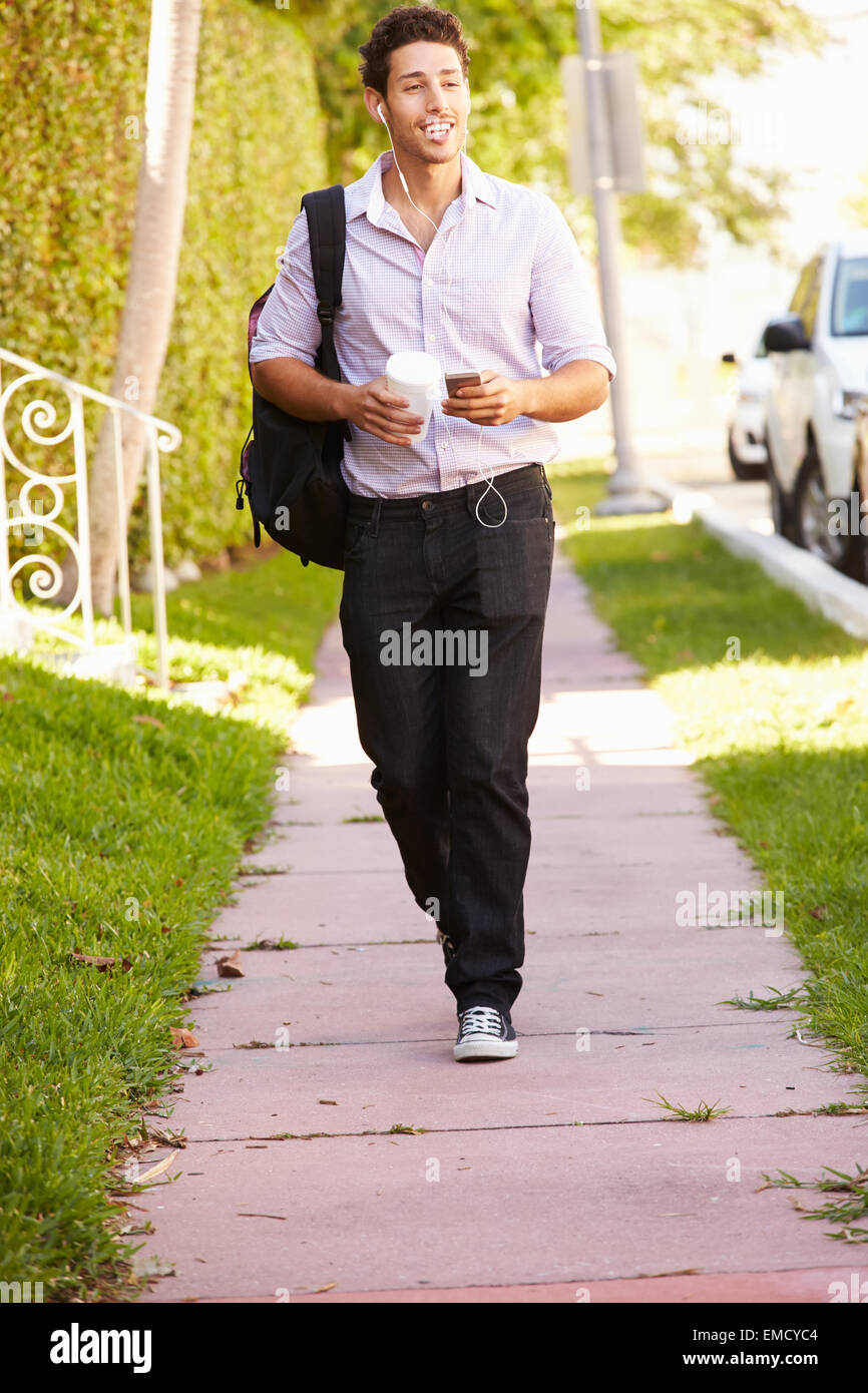Uomo che cammina lungo la strada a lavoro ascoltando musica Foto Stock