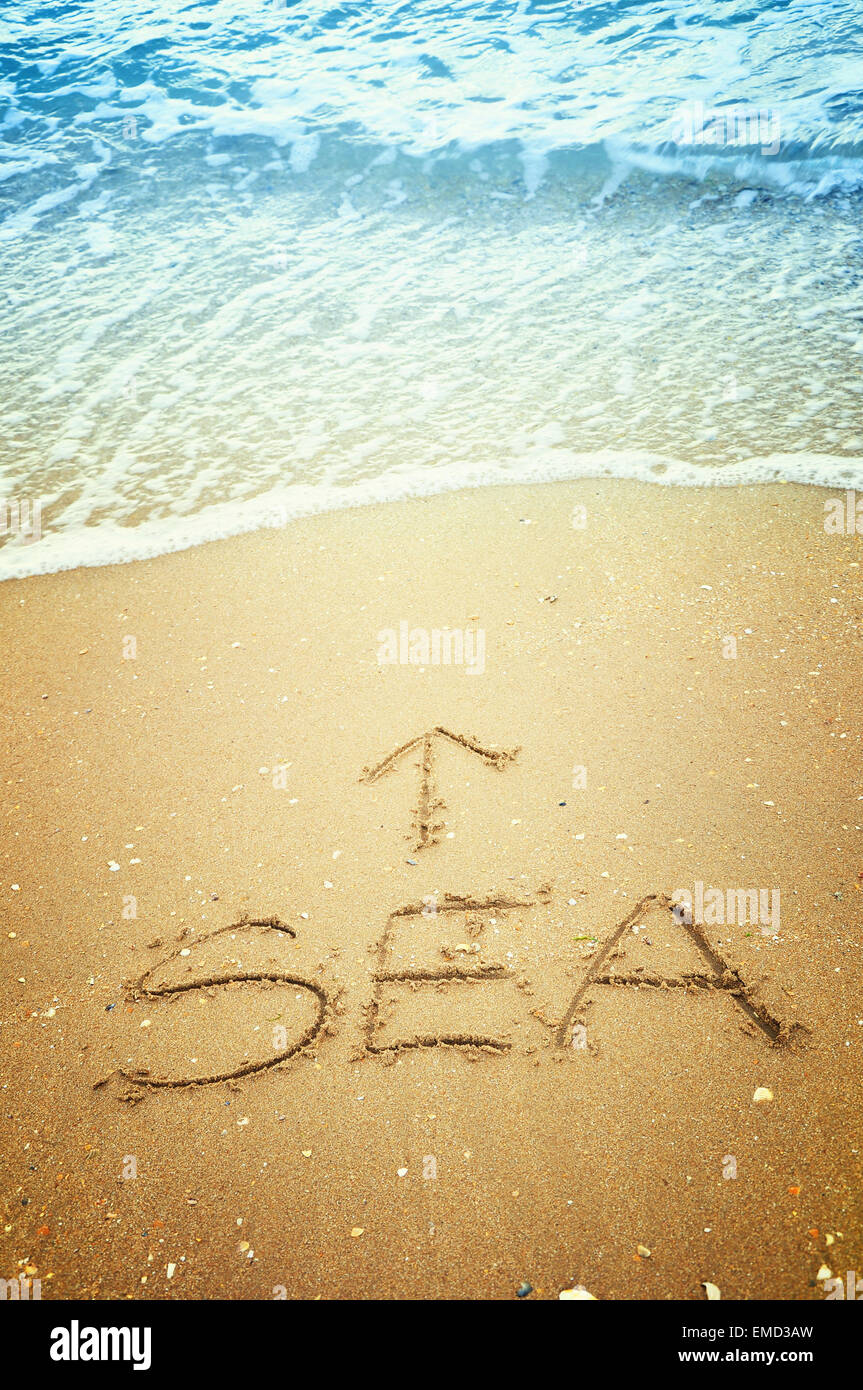 'Sea' e freccia scritto nella sabbia sulla spiaggia Foto Stock