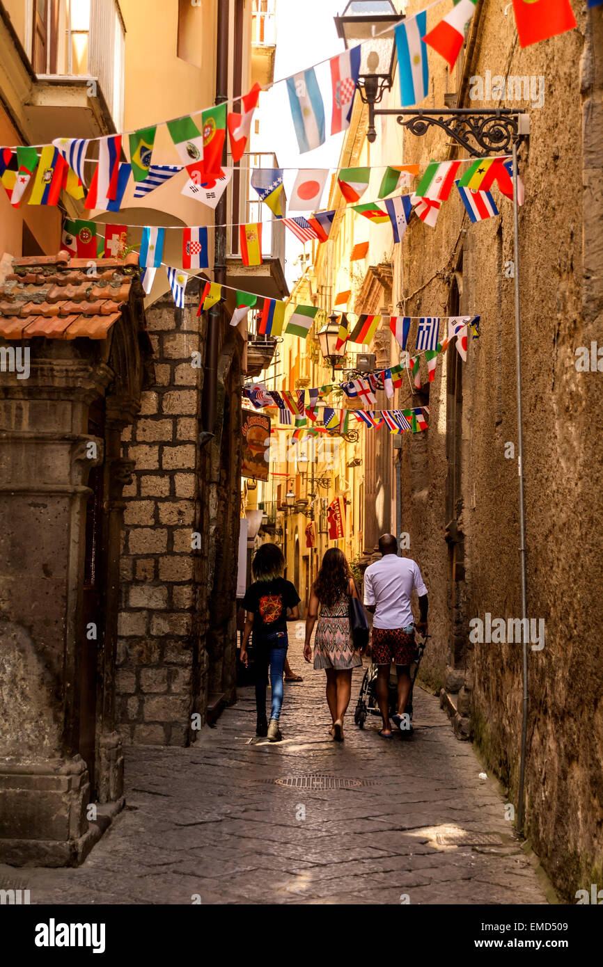 Una famiglia a piedi attraverso i vicoli in l'artista della zona di Sorrento. I vicoli sono decorate con le bandiere di molte nazionalità. Foto Stock
