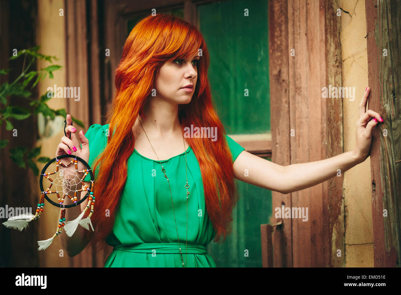 Creative Ritratto di Redhead giovane donna in abito verde con Dream Catcher nelle sue mani. Lunga e bellissima capelli rossi.Il fuoco selettivo Foto Stock