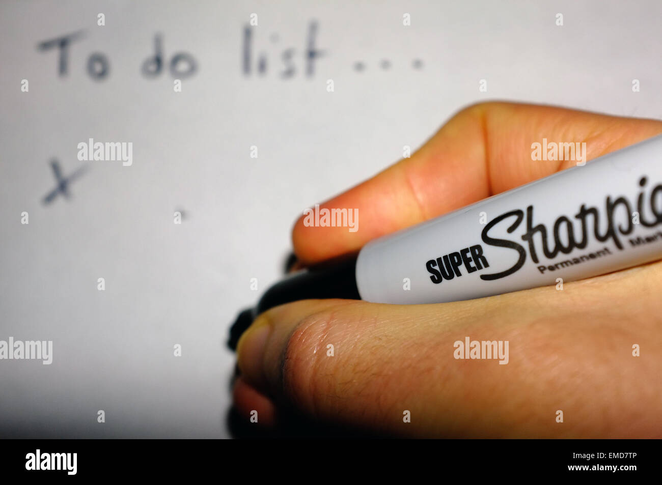 Una mano bianca tenendo un pennarello indelebile Sharpie pen scrivendo un 'Lista da fare su un foglio di carta. Foto Stock