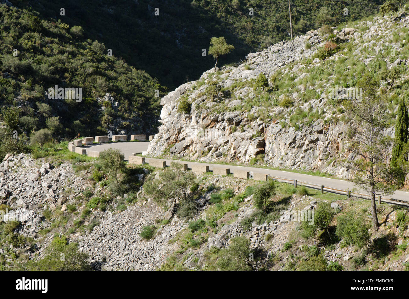 Avvolgimento stretto lastricata strada di montagna con basse barriere di pietra, Ojen, Andalusia, Spagna. Foto Stock