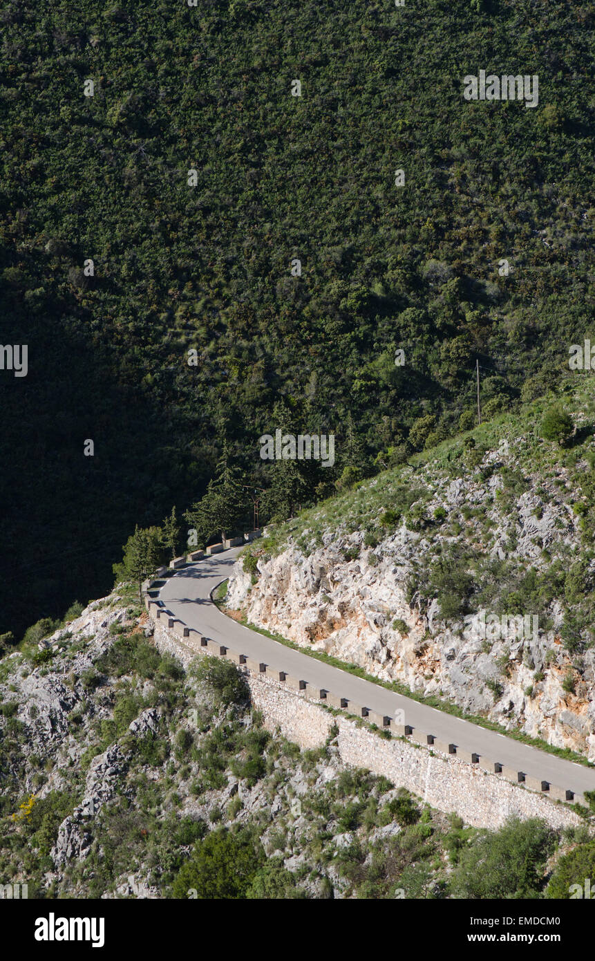 Avvolgimento stretto lastricata strada di montagna con basse barriere di pietra, Ojen, Andalusia, Spagna. Foto Stock