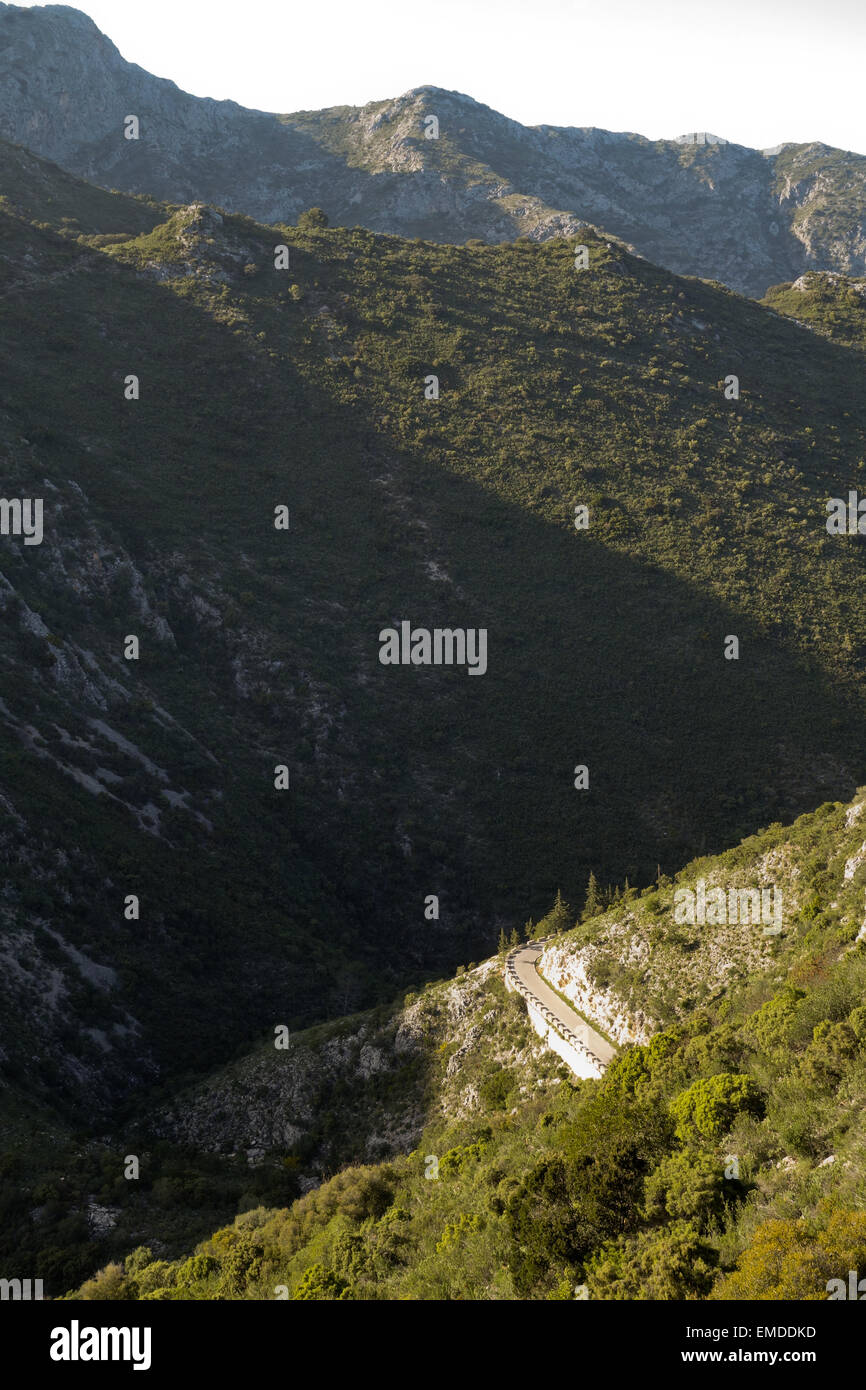 Avvolgimento stretto lastricata strada di montagna con basse barriere di pietra, Ojen, Andalusia, Spagna. Foto Stock