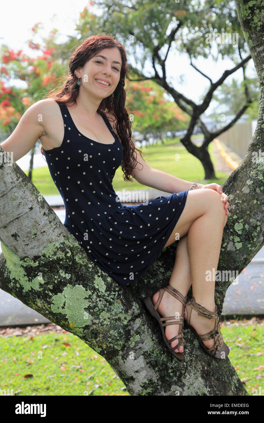 Giovane donna seduta su una struttura ad albero Foto Stock
