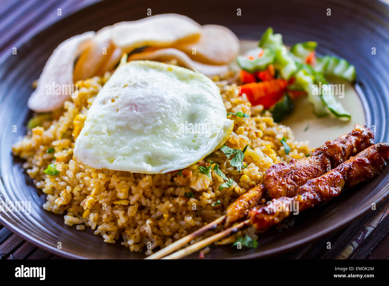 Nasi goreng (indonesiano ricetta tradizionale con riso fritto, Uovo fritto, cracker ai gamberi e carne su bistecche o sates). Foto Stock