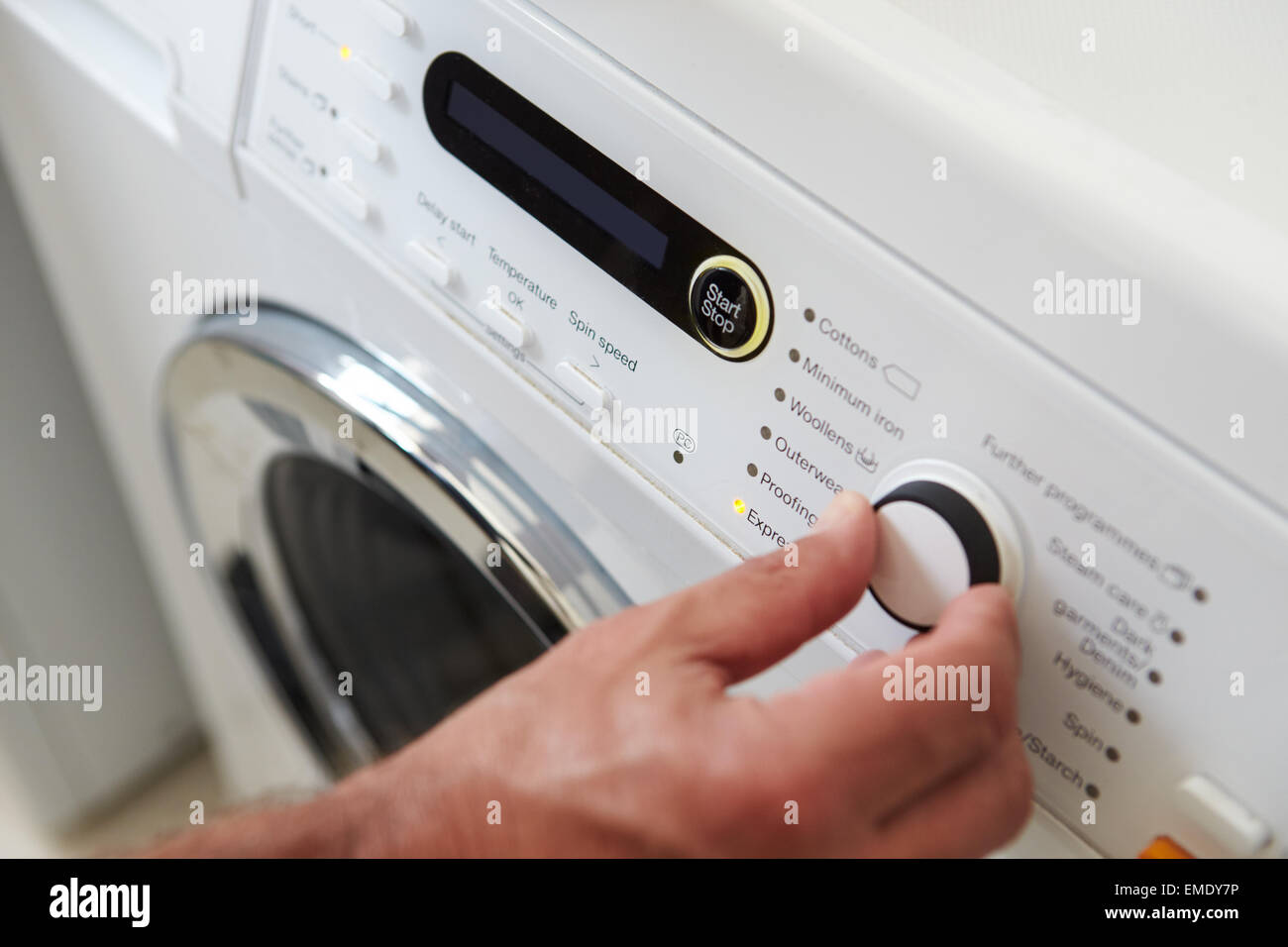 Close up uomo scegliendo il programma di ciclo sulla macchina di lavaggio Foto Stock