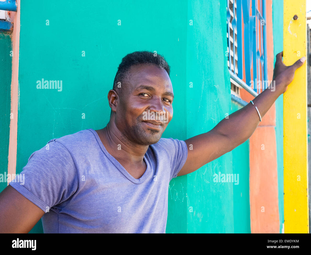 Un uomo afro-cubane si appoggia con il suo braccio contro colorate Pareti del al di fuori delle case vicine. Foto Stock