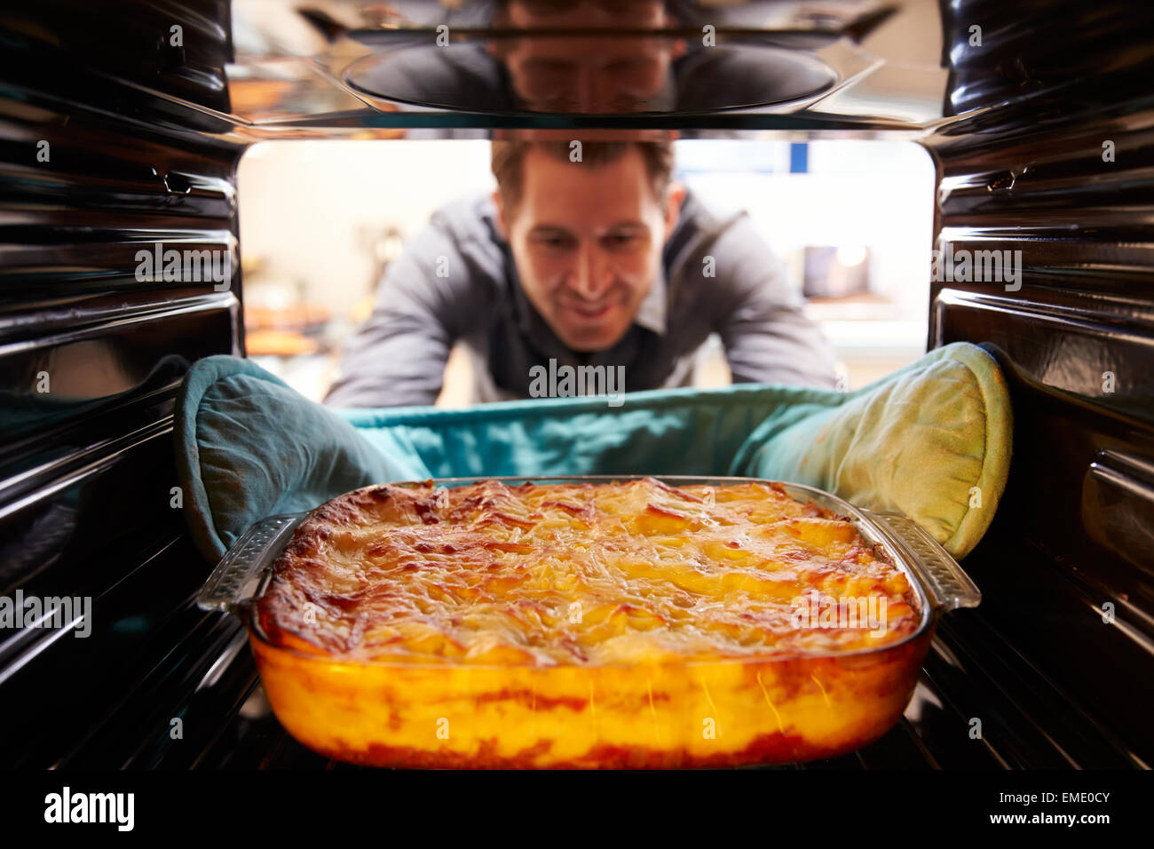 L'uomo tenendo piatto cucinato di lasagne al di fuori del forno Foto Stock