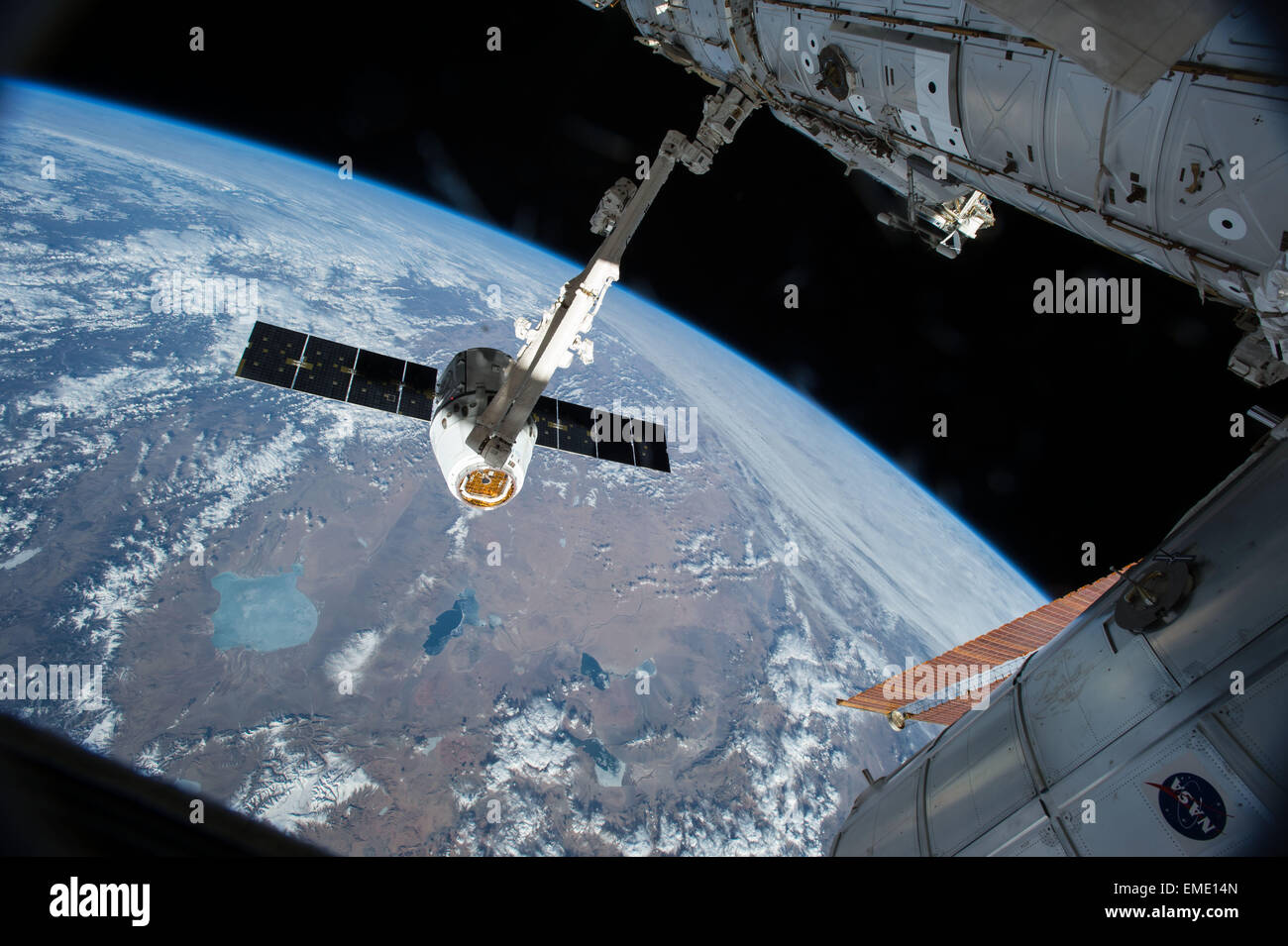 Il Canadarm 2 raggiunge la benna mordente SpaceX Dragon cargo astronave e prepararla per tirare in porta sulla Stazione Spaziale Internazionale Aprile 17, 2015 in orbita intorno alla terra. La capsula Dragon è portatore di forniture e cargo per equipaggio a bordo della ISS. Foto Stock